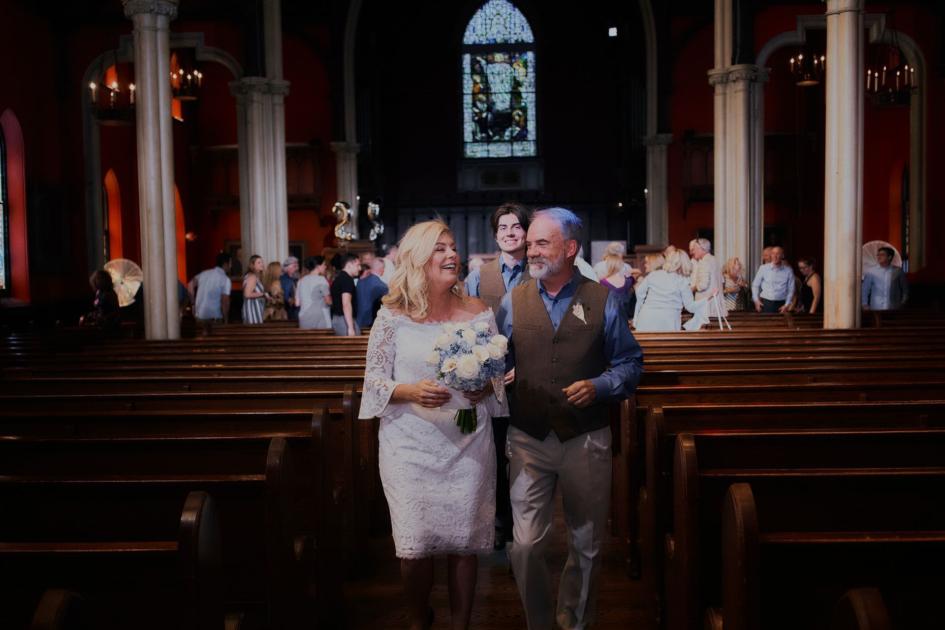 A bride and groom are walking down the aisle of a church.