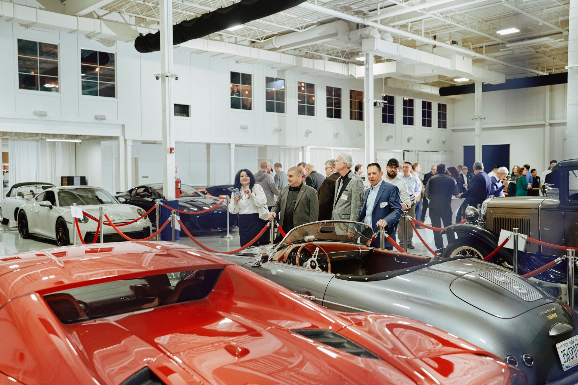 A group of people are looking at cars in a garage.