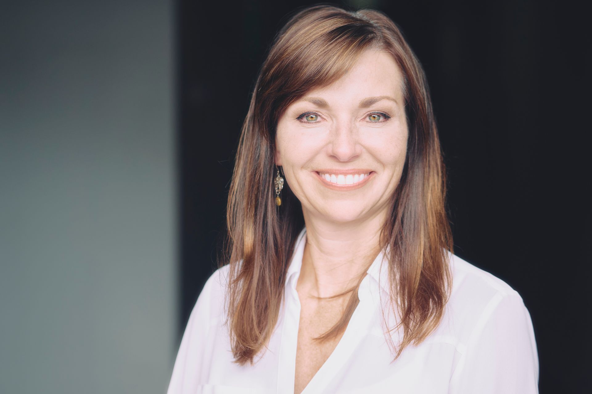 A woman in a white shirt is smiling for the camera.