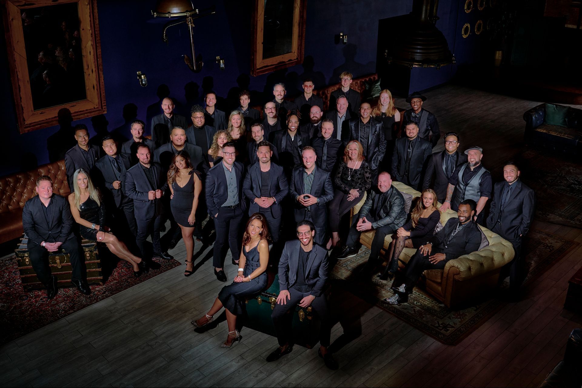 A large group of people are posing for a picture in a dark room.