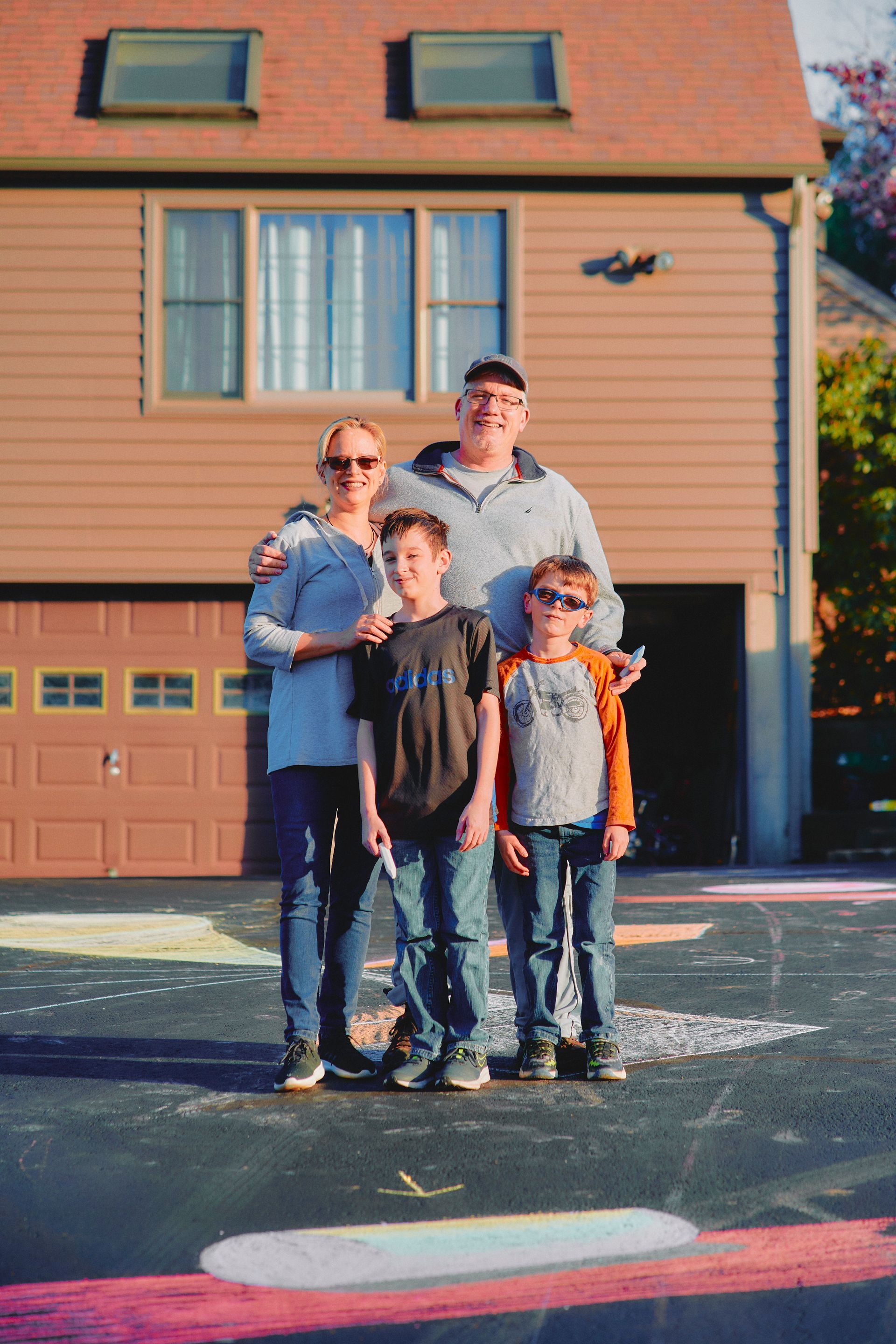 A family is posing for a picture in front of their house.