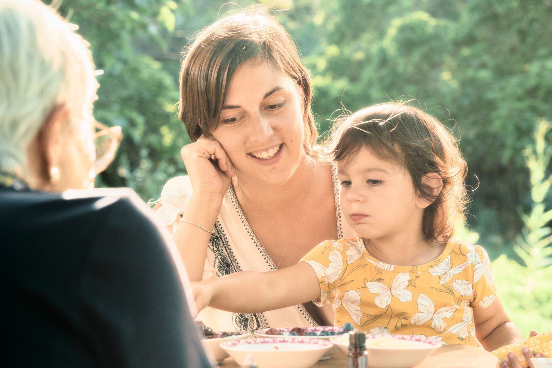 A woman and a little girl are sitting at a table eating food.