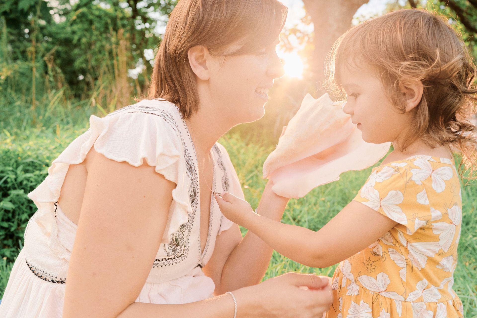 A woman and a little girl are playing in the grass.