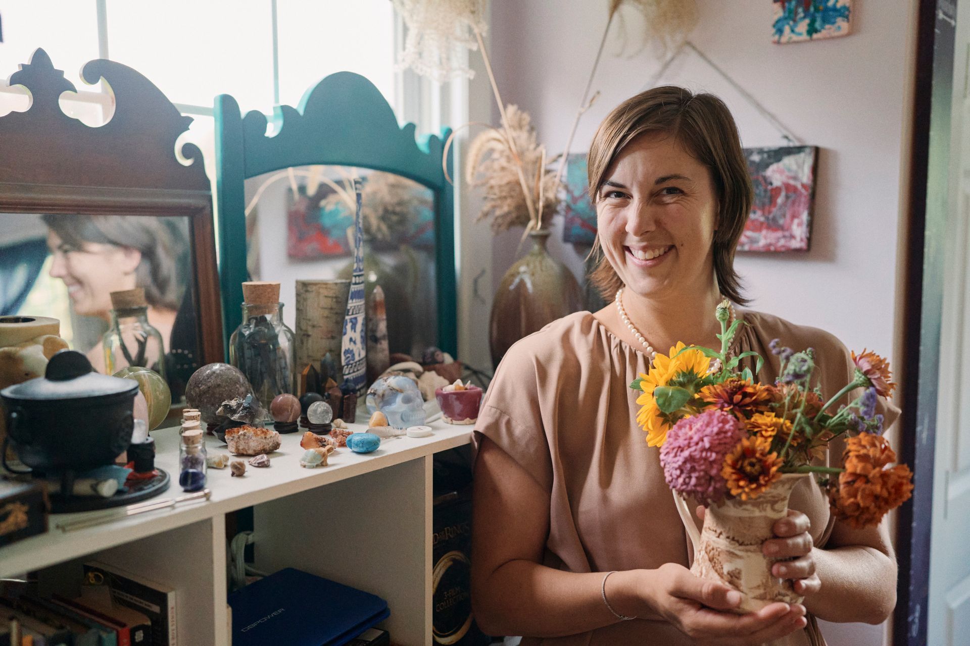 A woman is holding a vase of flowers in a room.