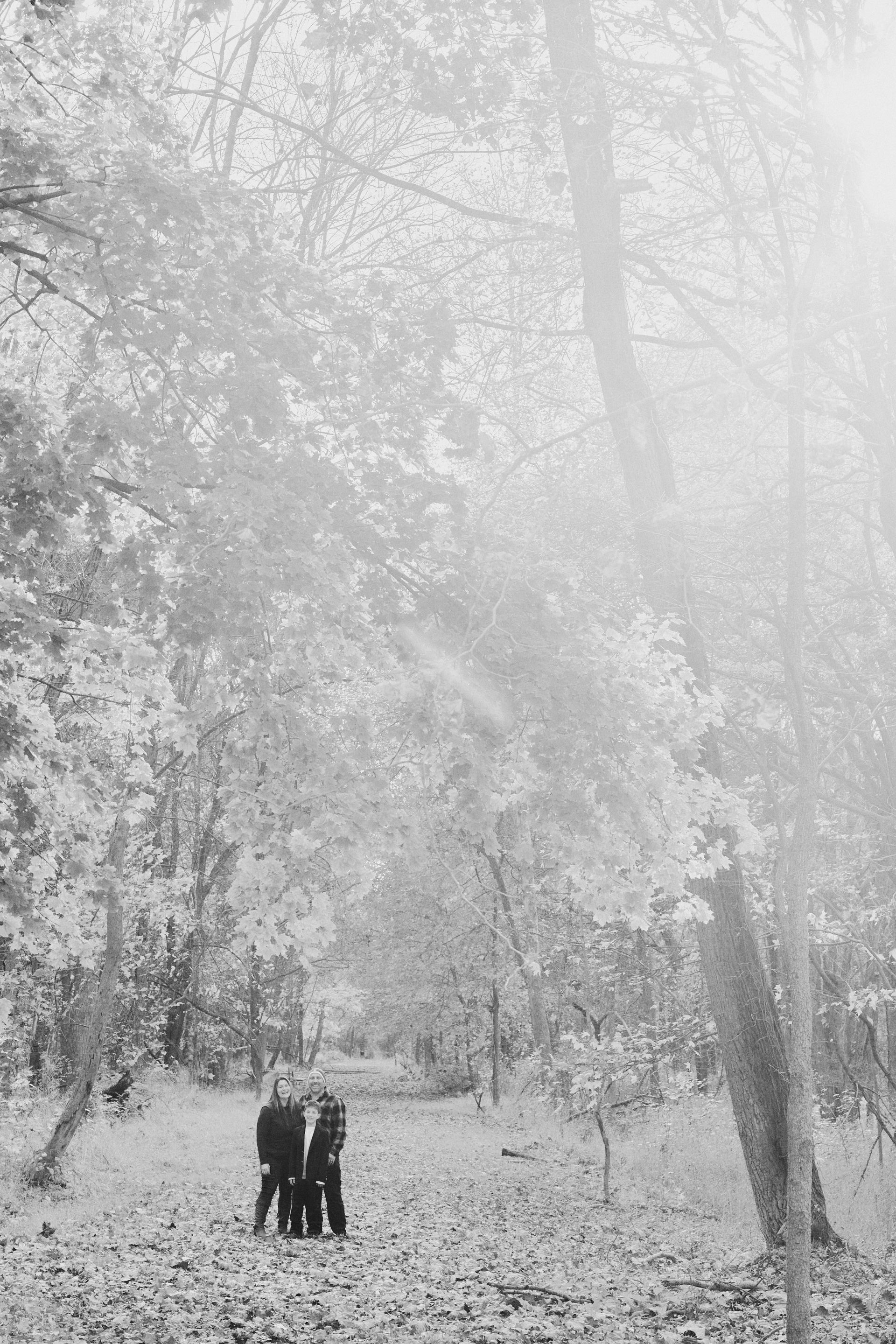 A black and white photo of a couple standing in a snowy forest.