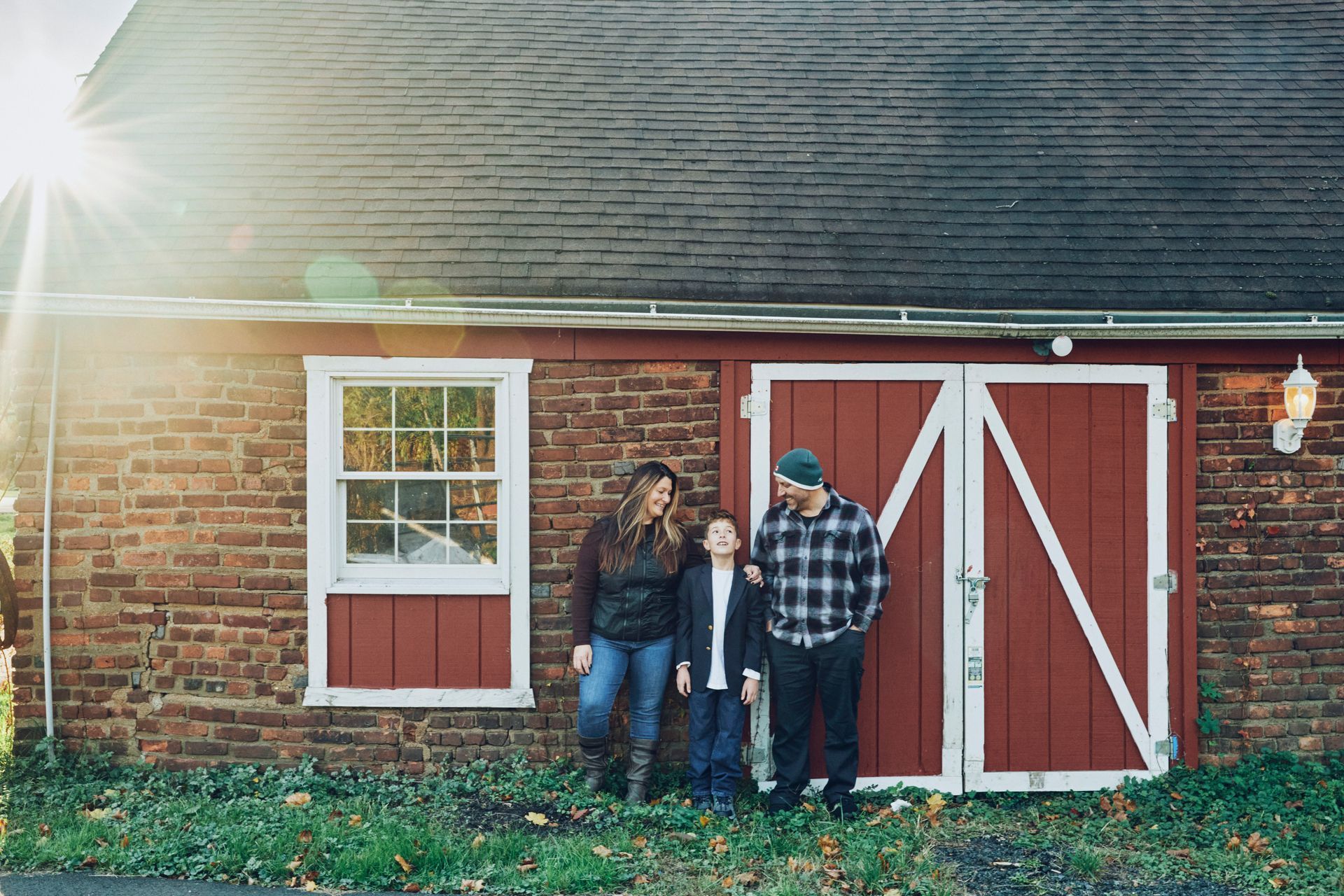 A family is standing in front of a red barn.