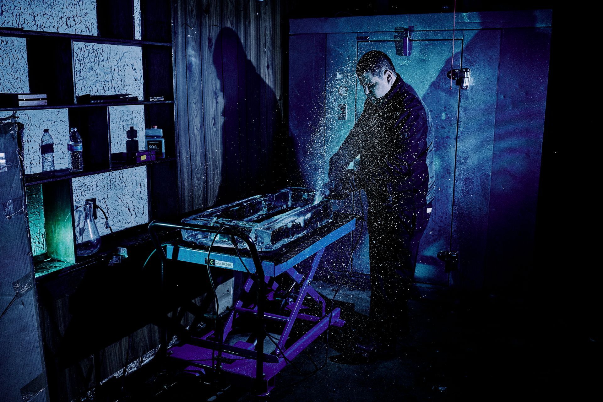 A man is standing in front of a purple table in a dark room.