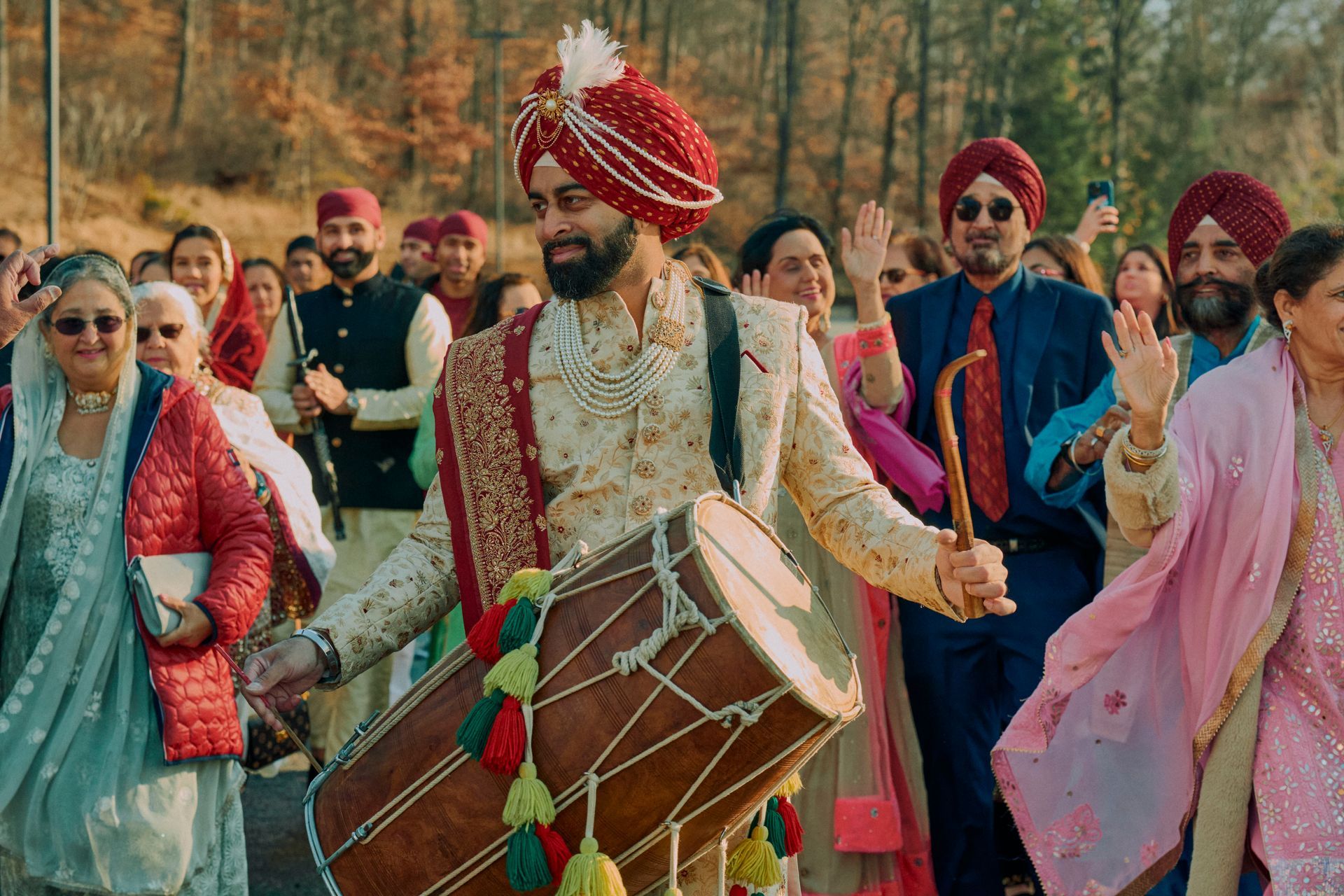 A man in a turban is playing a drum in front of a crowd of people.