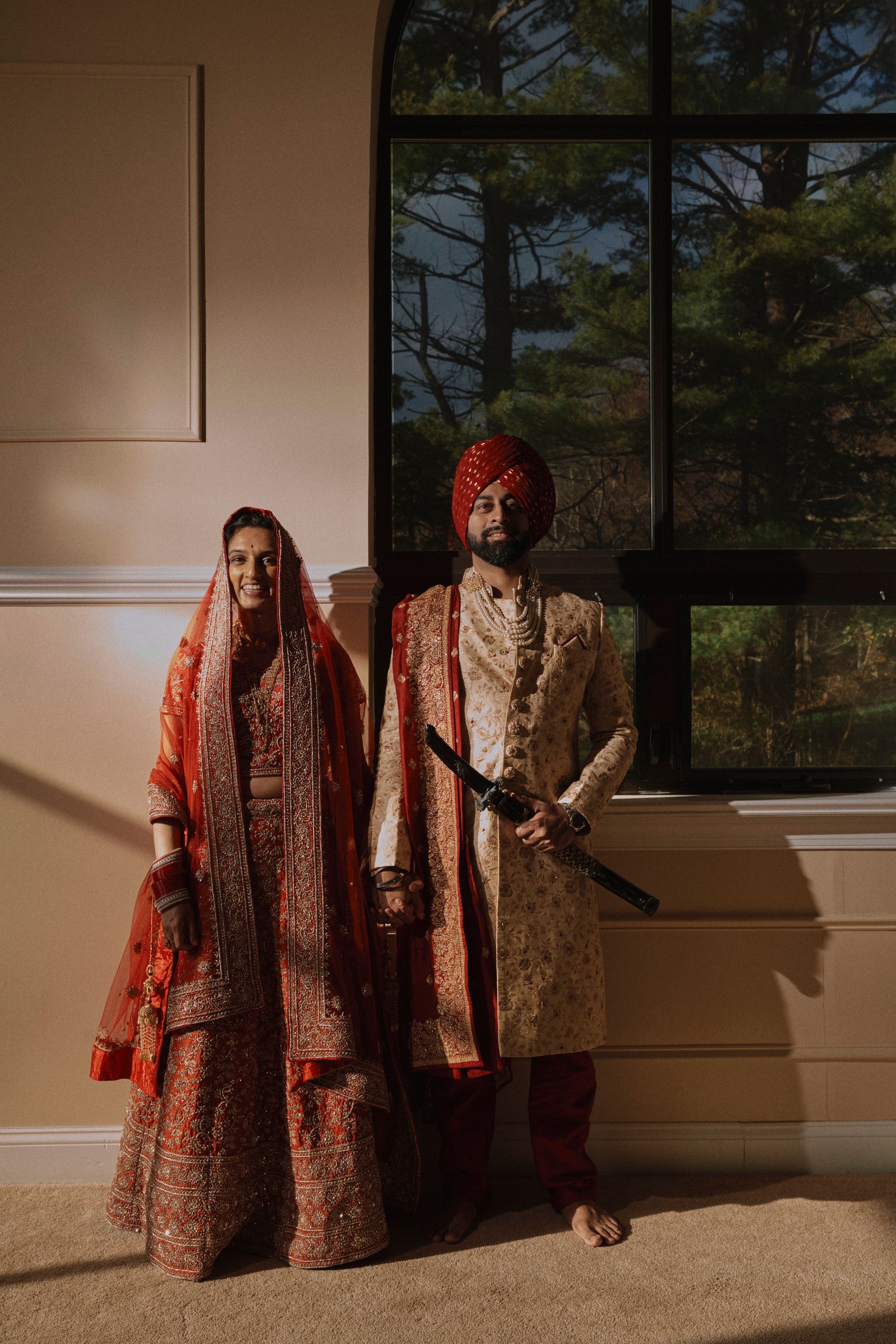 A bride and groom are posing for a picture in front of a window.