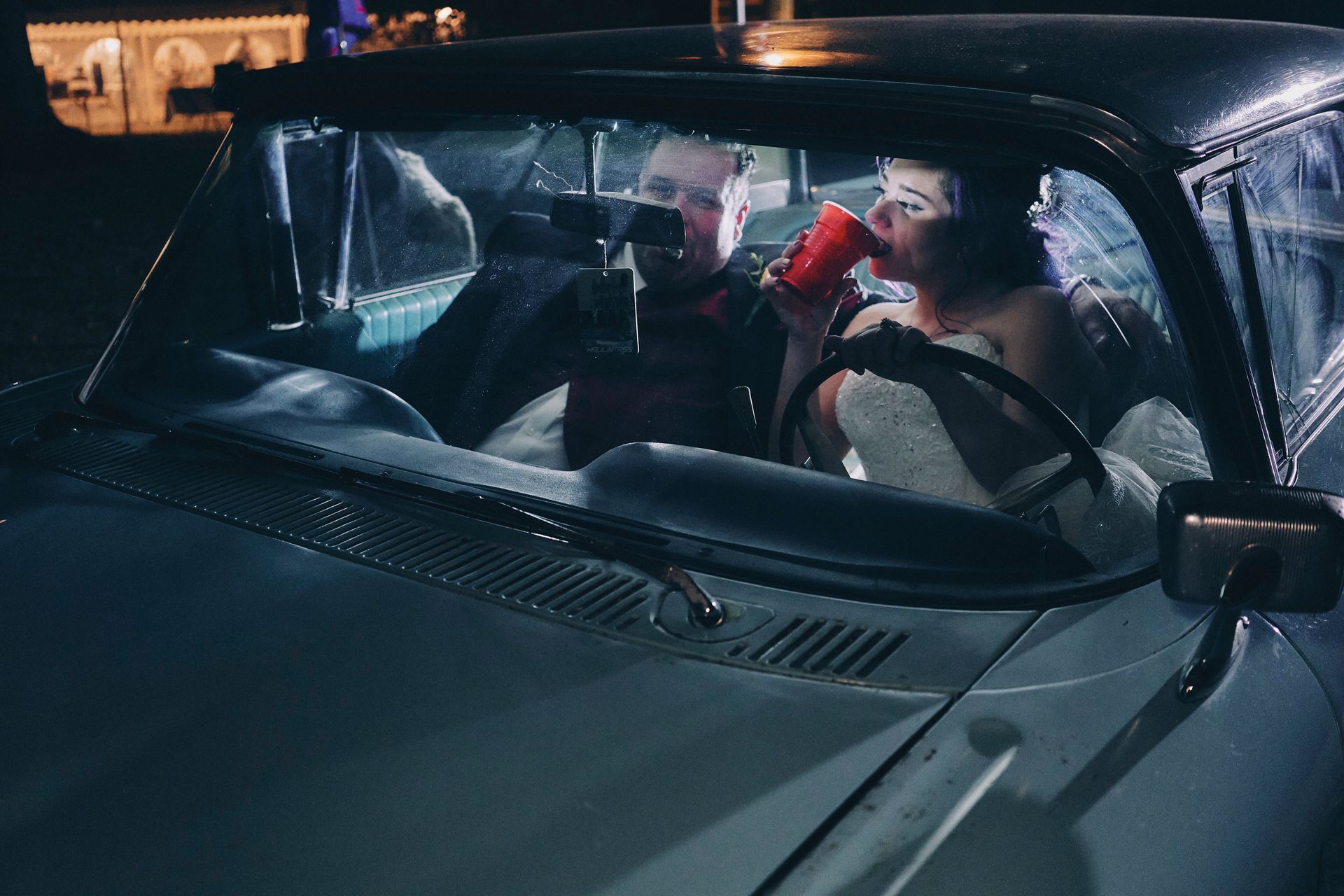 A woman is drinking from a red cup while sitting in a car.