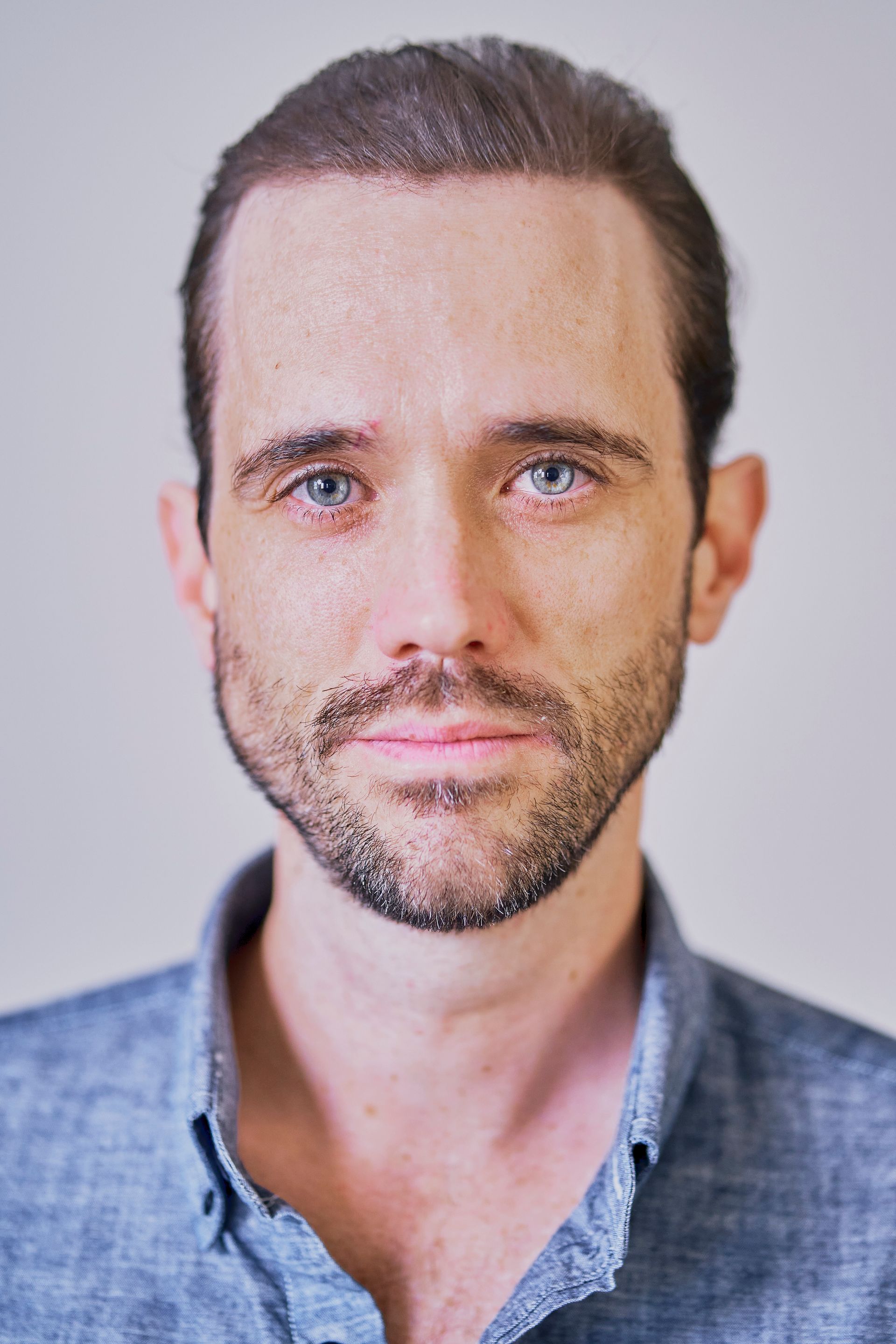 A man with a beard and blue eyes is looking at the camera.