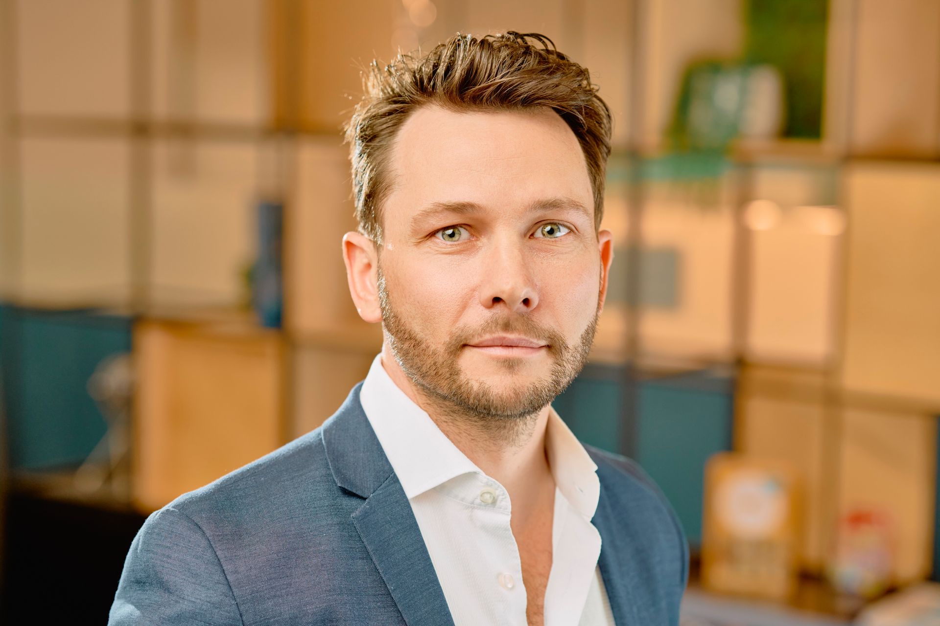 Portrait of a man in a blue blazer and white shirt in a modern office setting