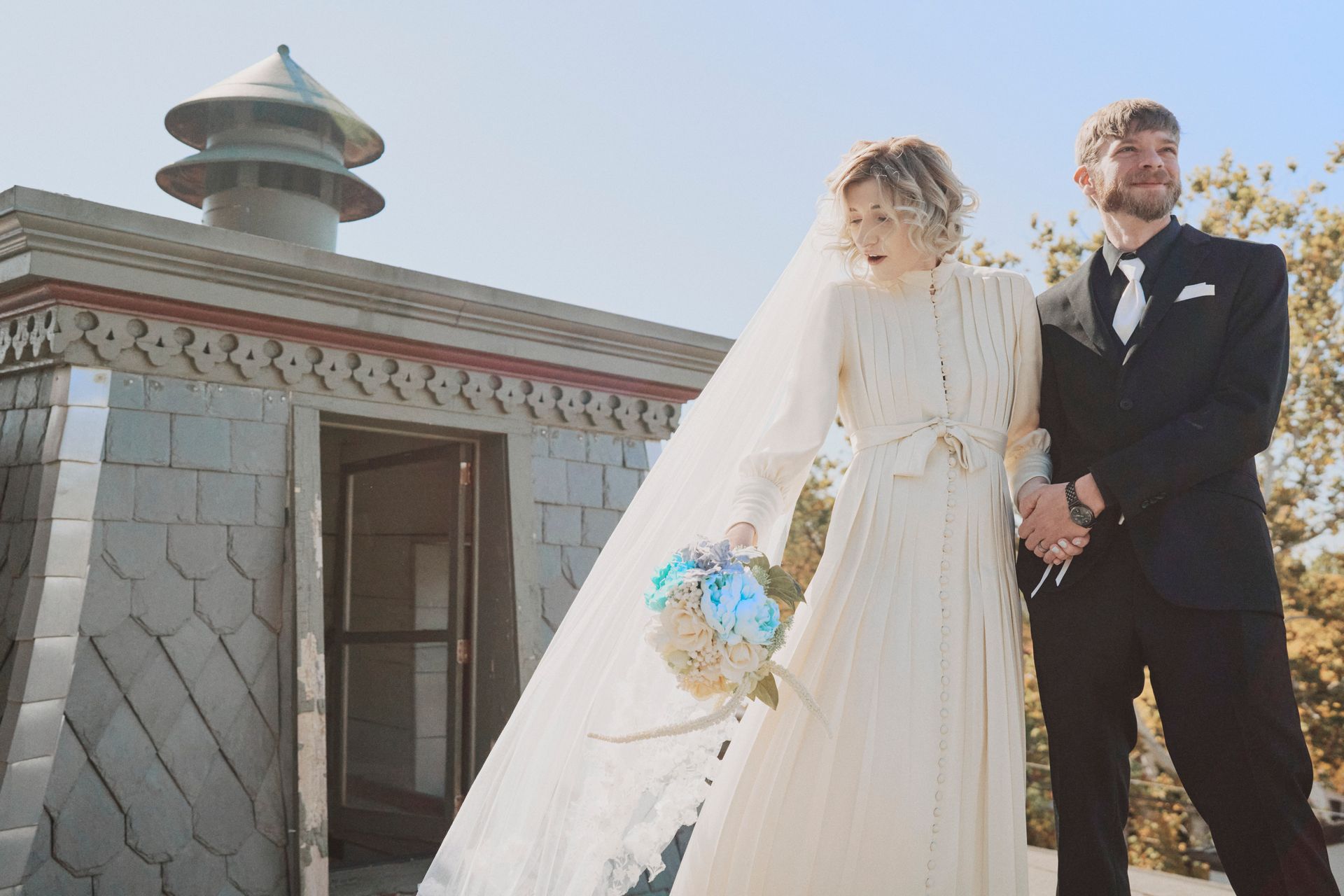A bride and groom are standing next to each other in front of a building.