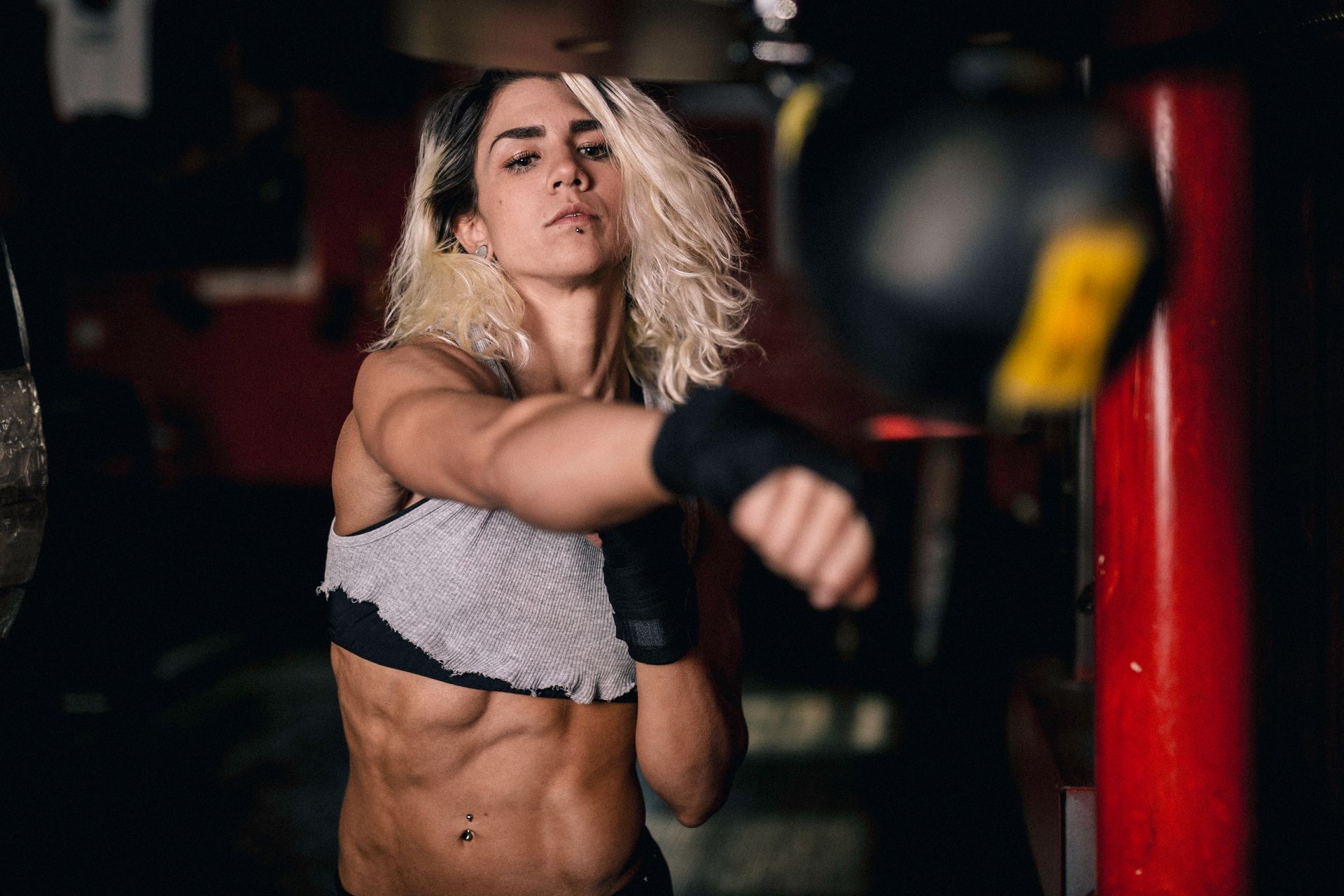 Athlete throwing a punch in a gym, with a red punching bag in the background.