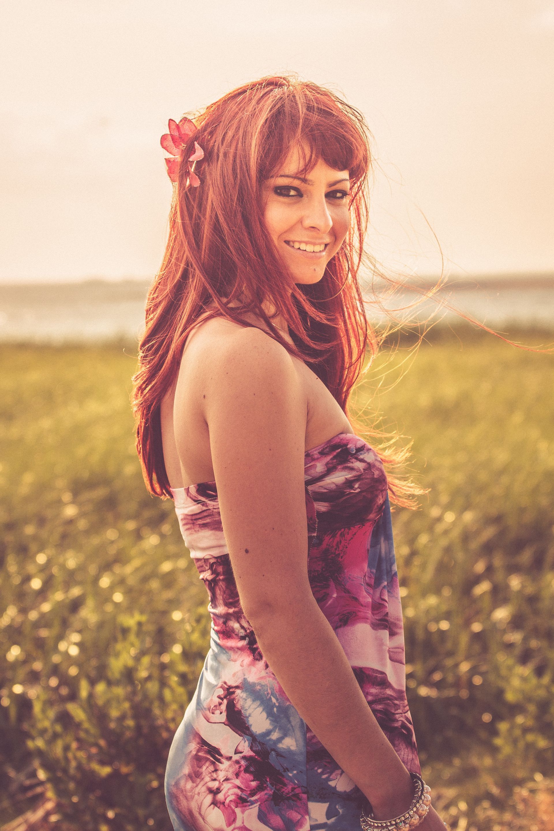 A woman in a floral dress is standing in a field of flowers.