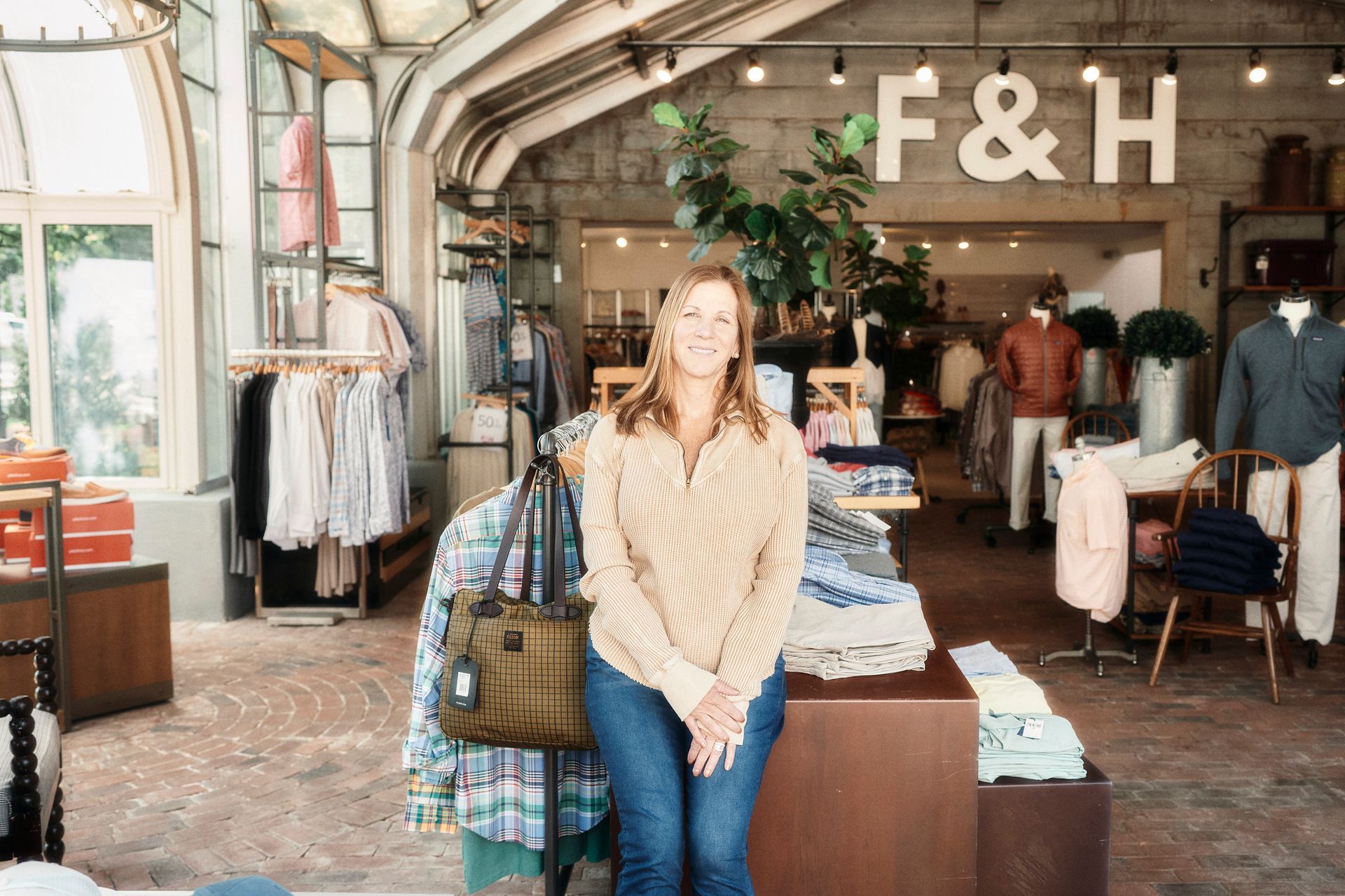 A woman is sitting on a table in a clothing store.