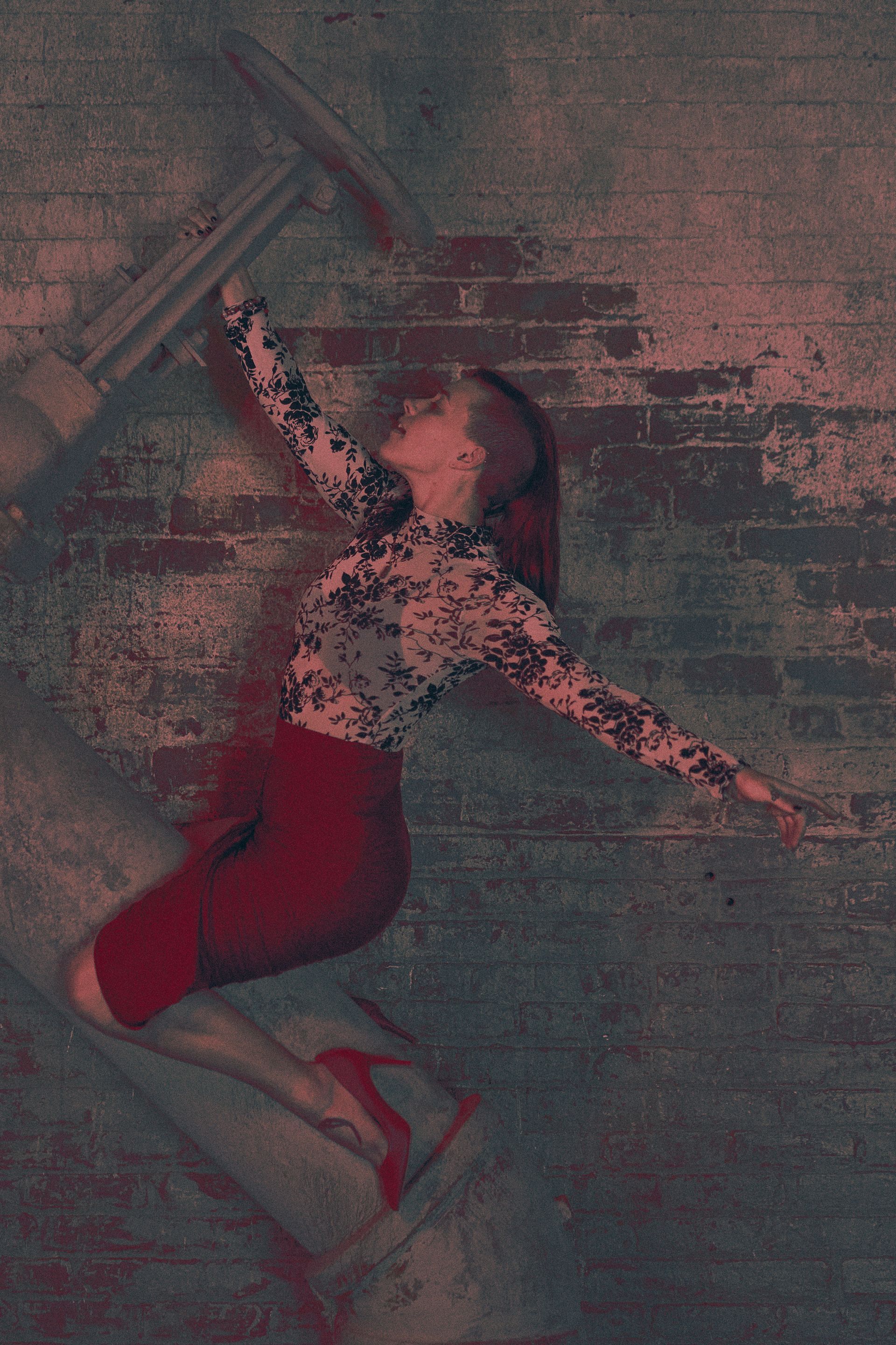 A woman is flying through the air in front of a brick wall.