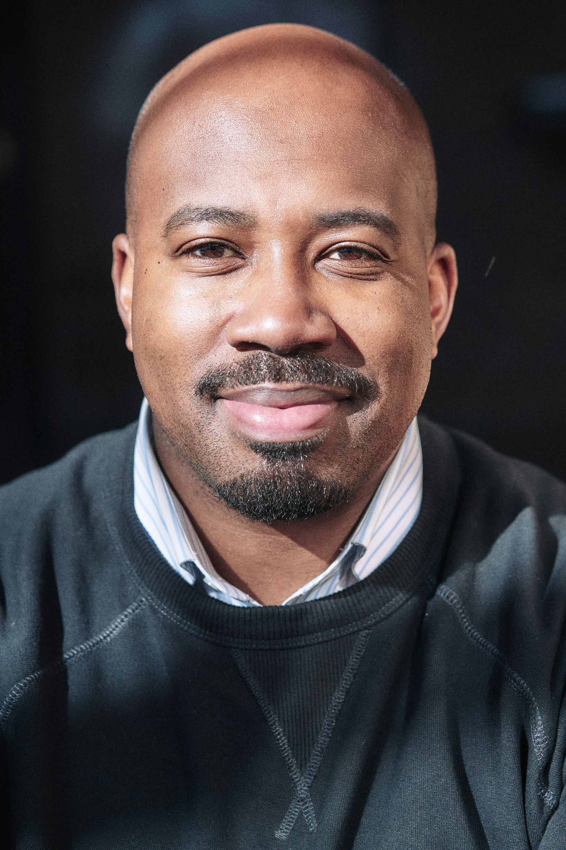 A bald man with a beard and mustache is smiling for the camera.