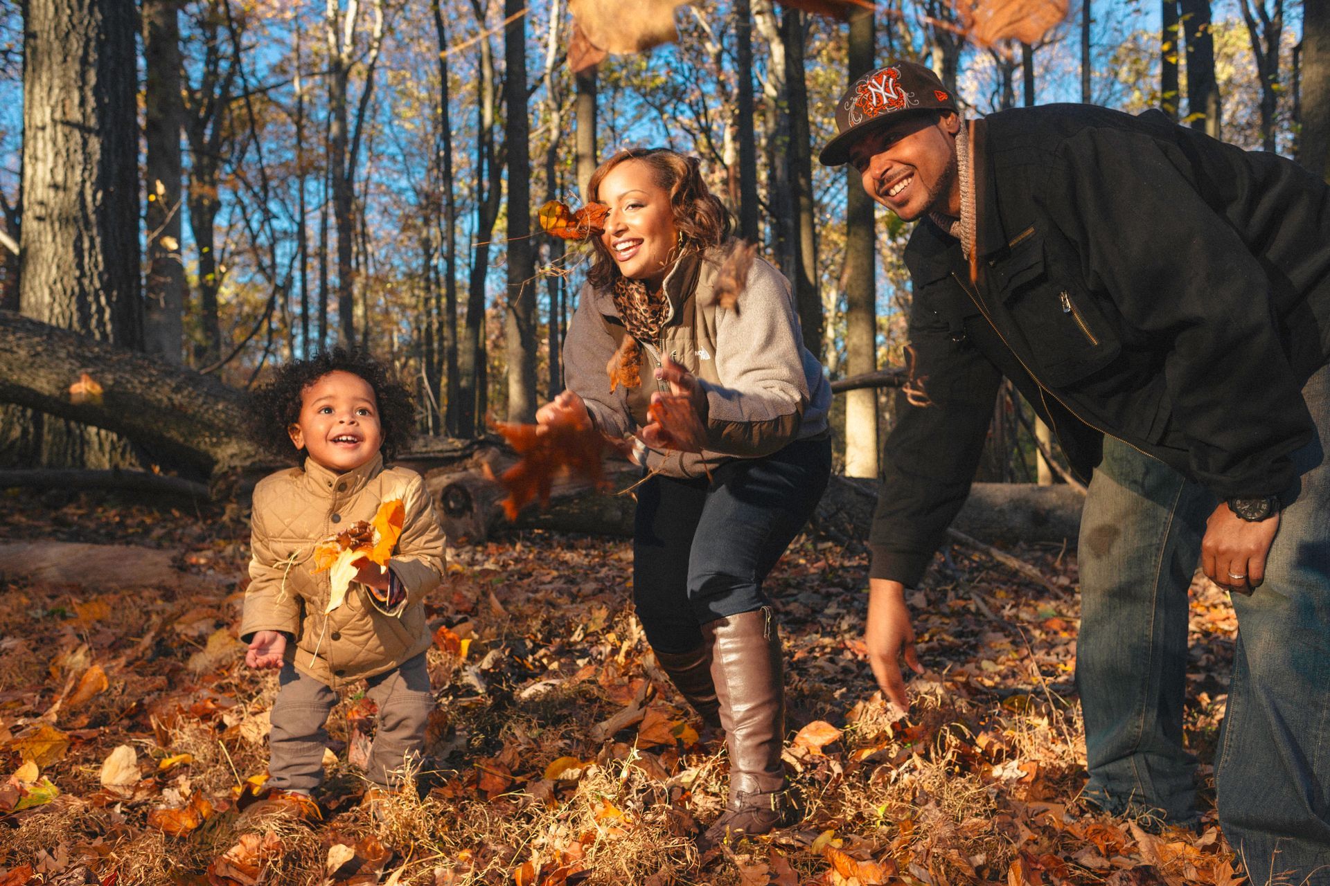 A family is playing with leaves in the woods.