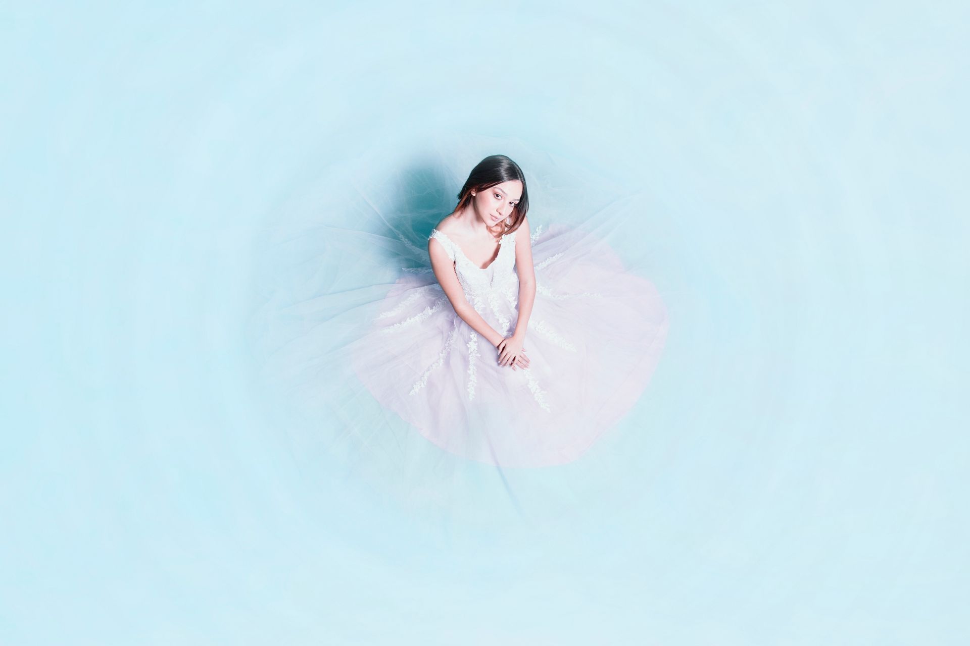 A woman in a pink tutu is sitting on a blue surface.