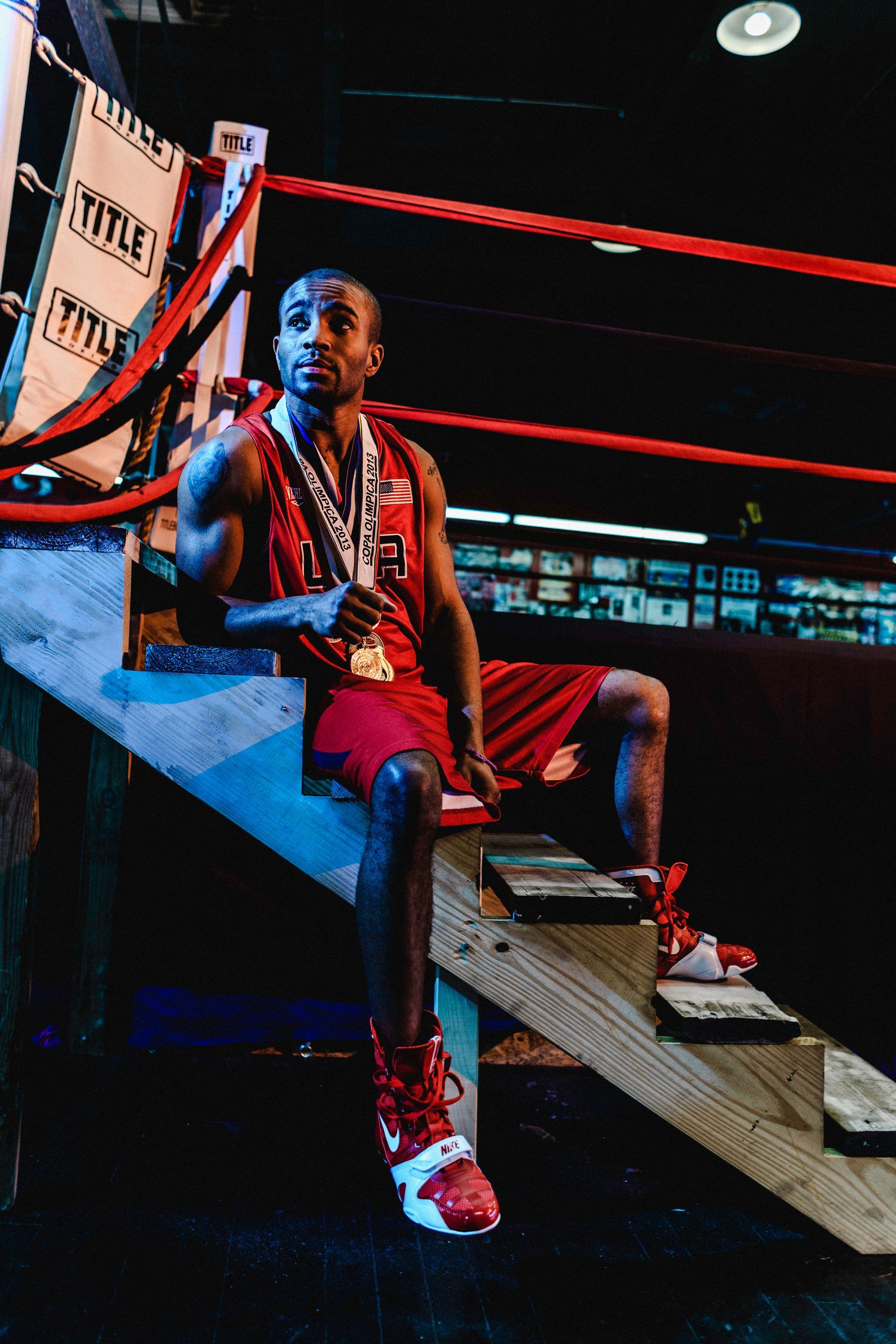 A boxer is sitting on the steps of a boxing ring.