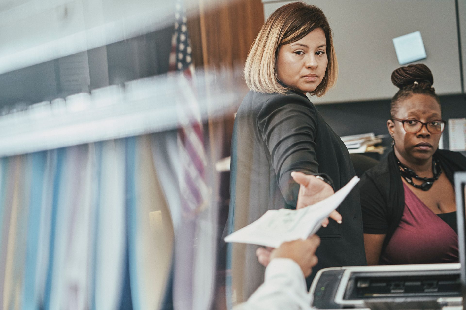 A woman is handing a piece of paper to another woman.