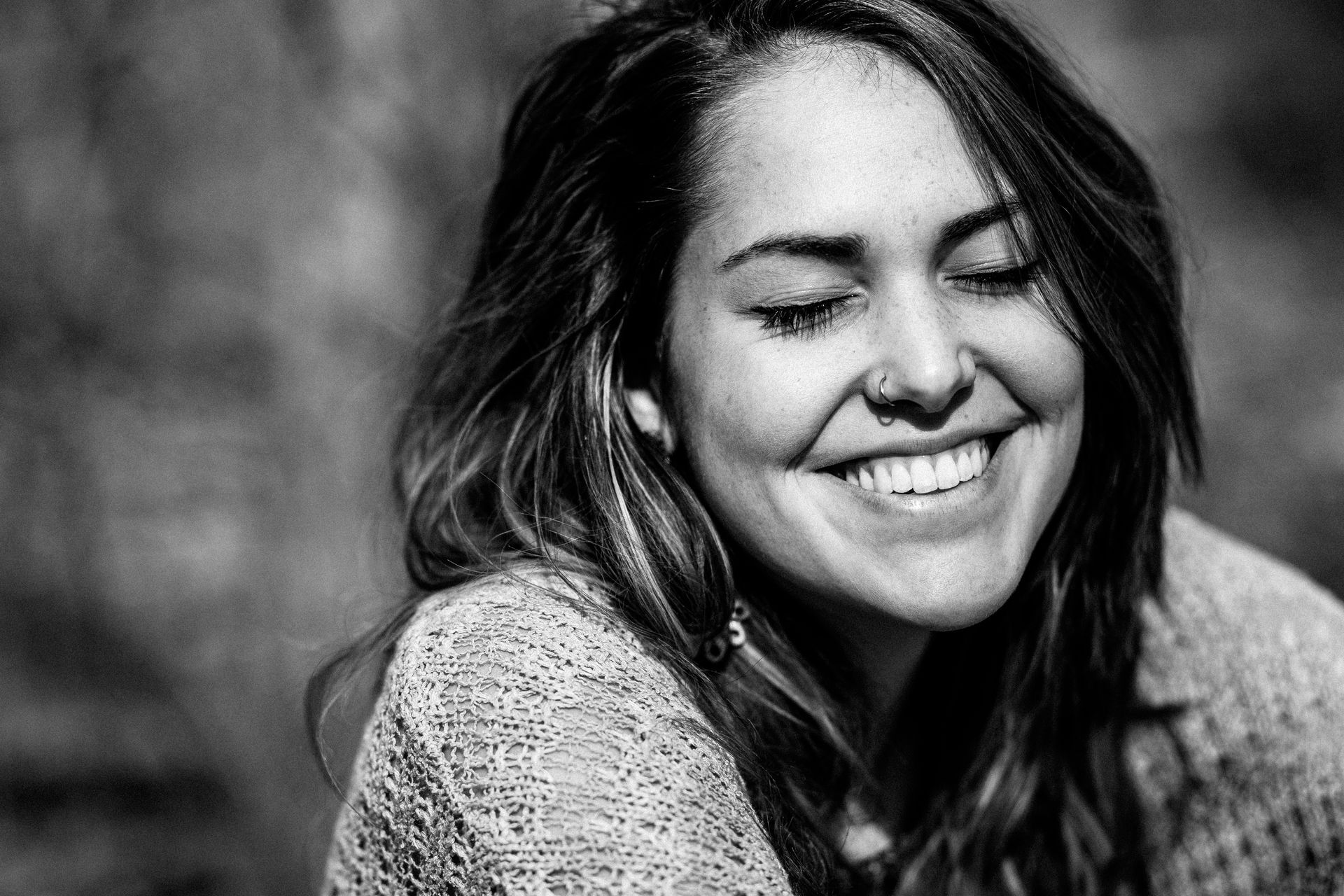 A black and white photo of a woman smiling with her eyes closed.