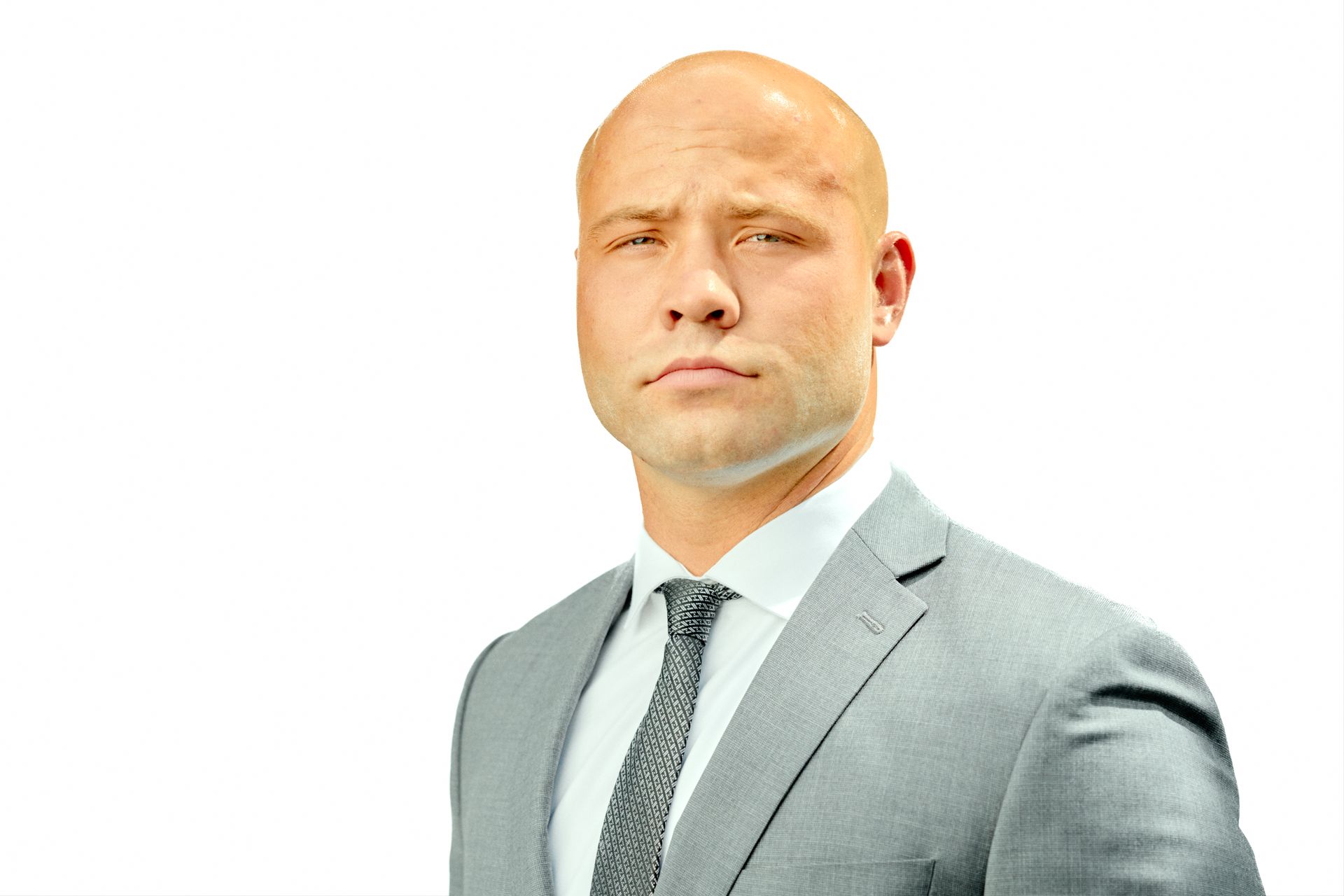 Bald man in a gray suit and tie, looking forward with a serious expression on a white background
