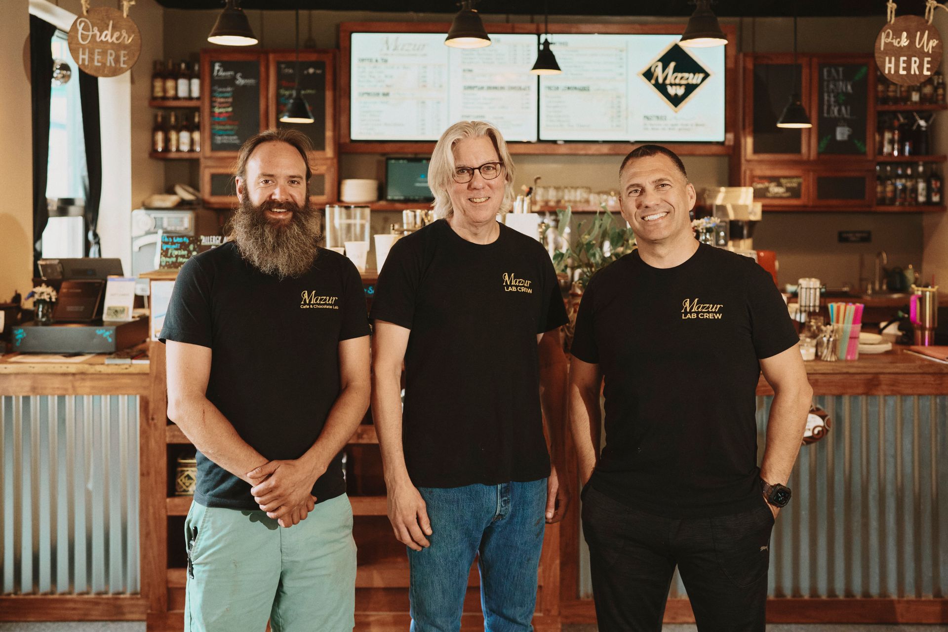 Three men are standing next to each other in a restaurant.