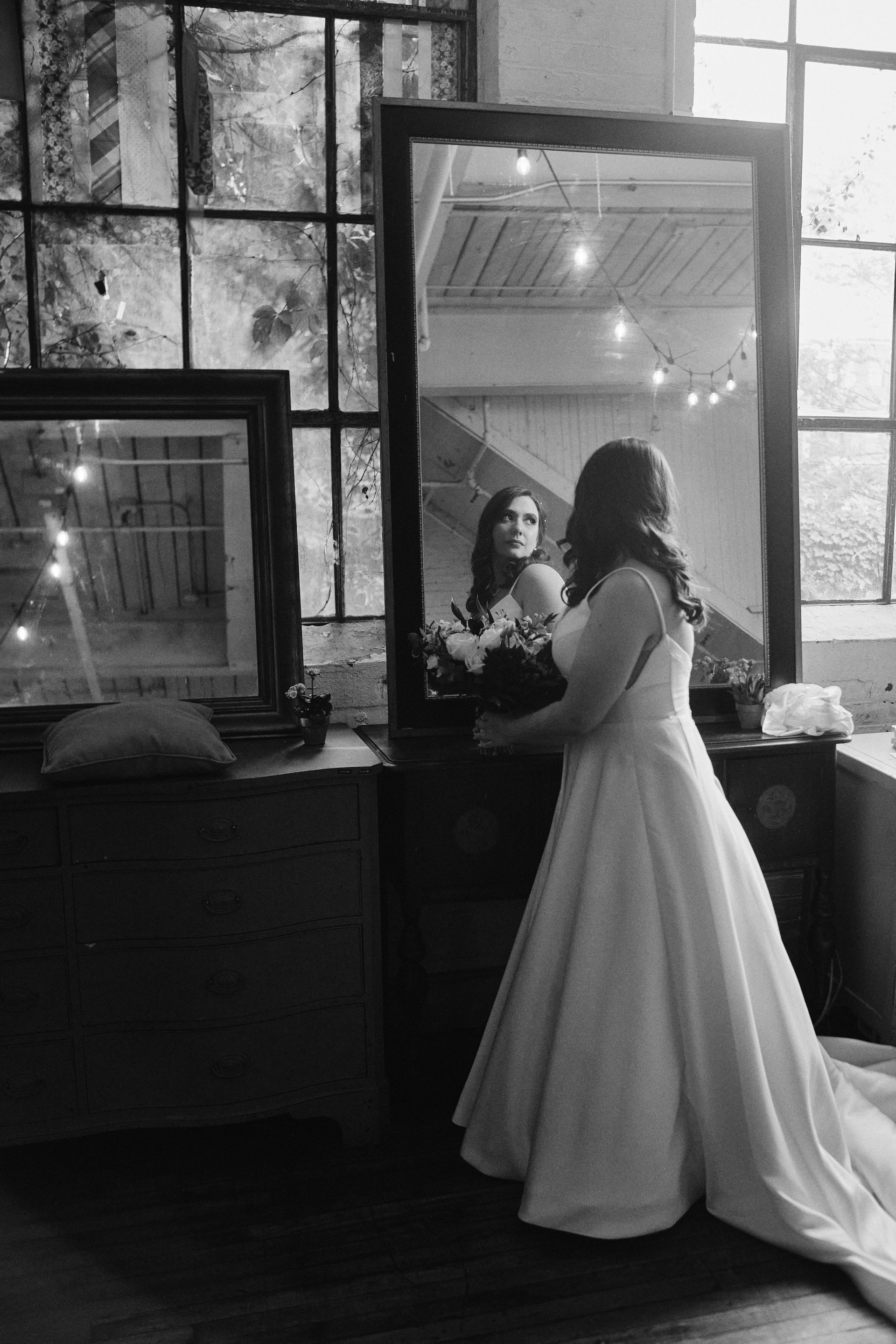 A woman in a wedding dress is standing in front of a mirror.