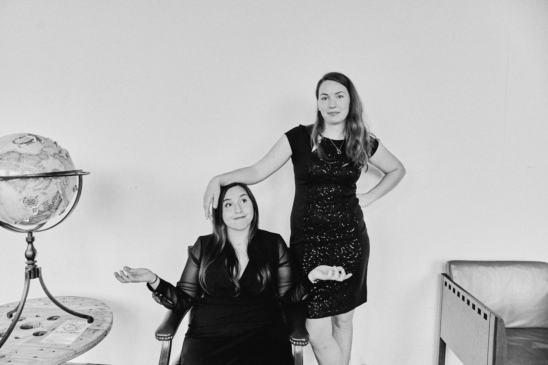 A black and white photo of two women standing next to each other in front of a globe.