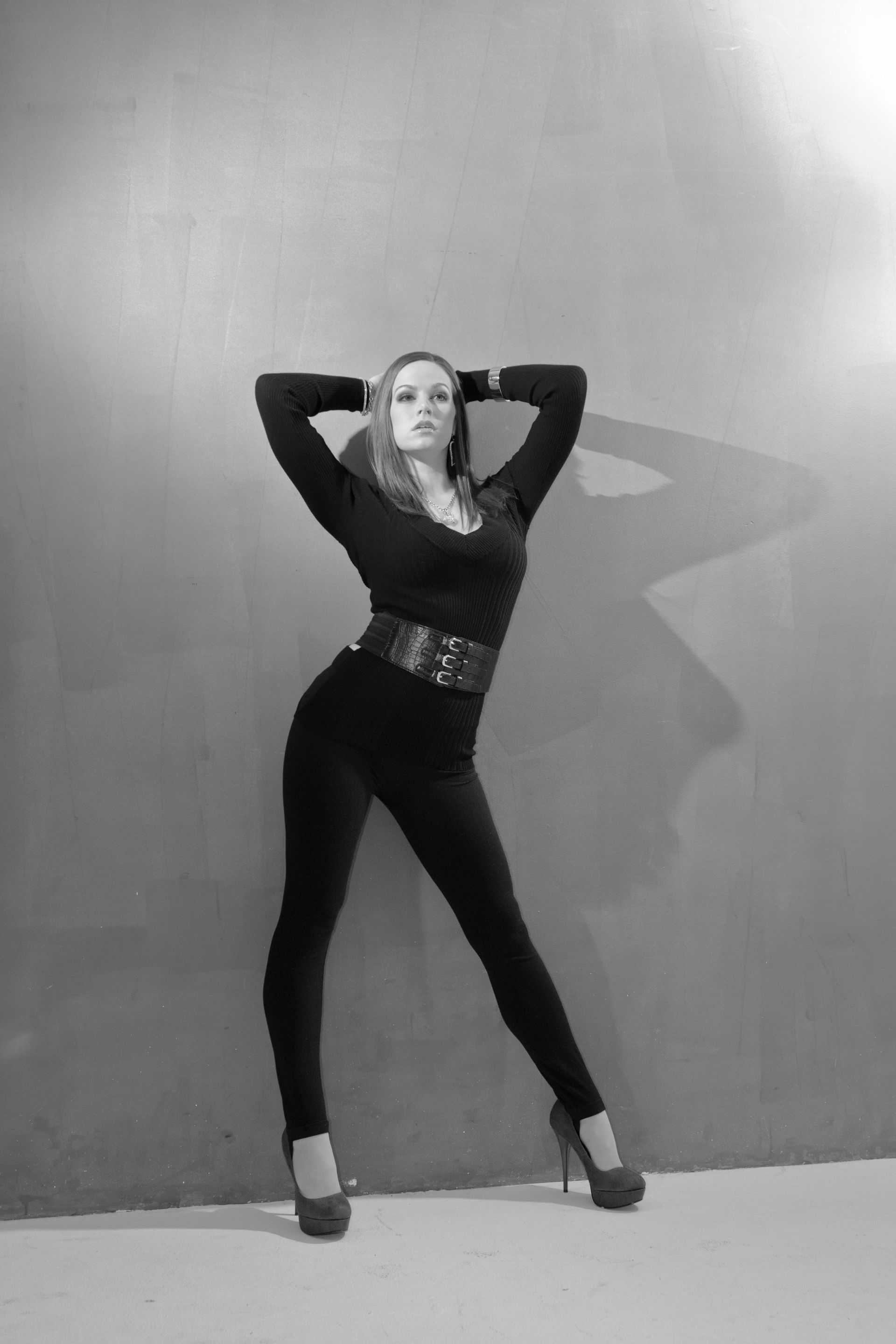 A black and white photo of a woman standing in front of a wall.