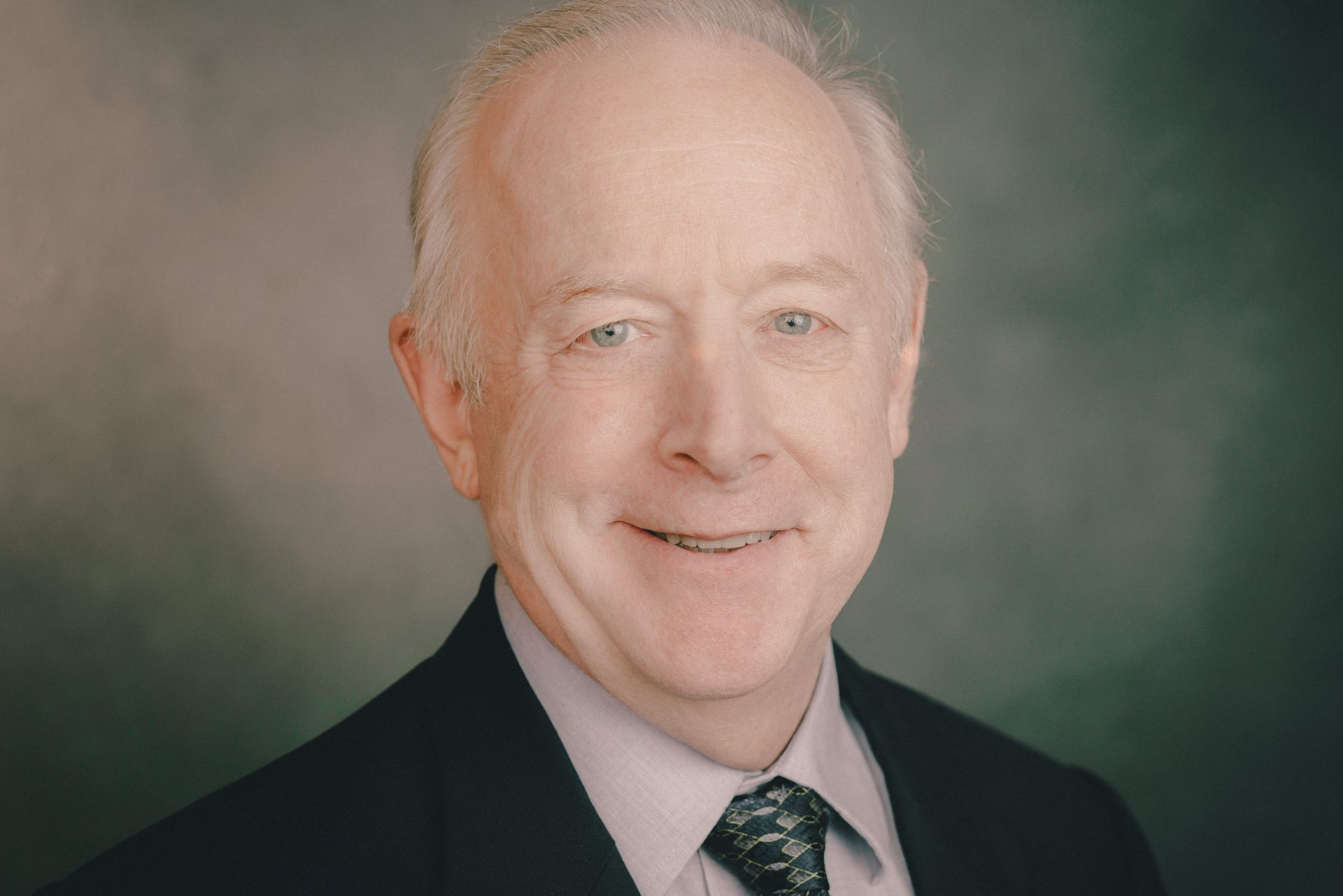 A man in a suit and tie is smiling for the camera.
