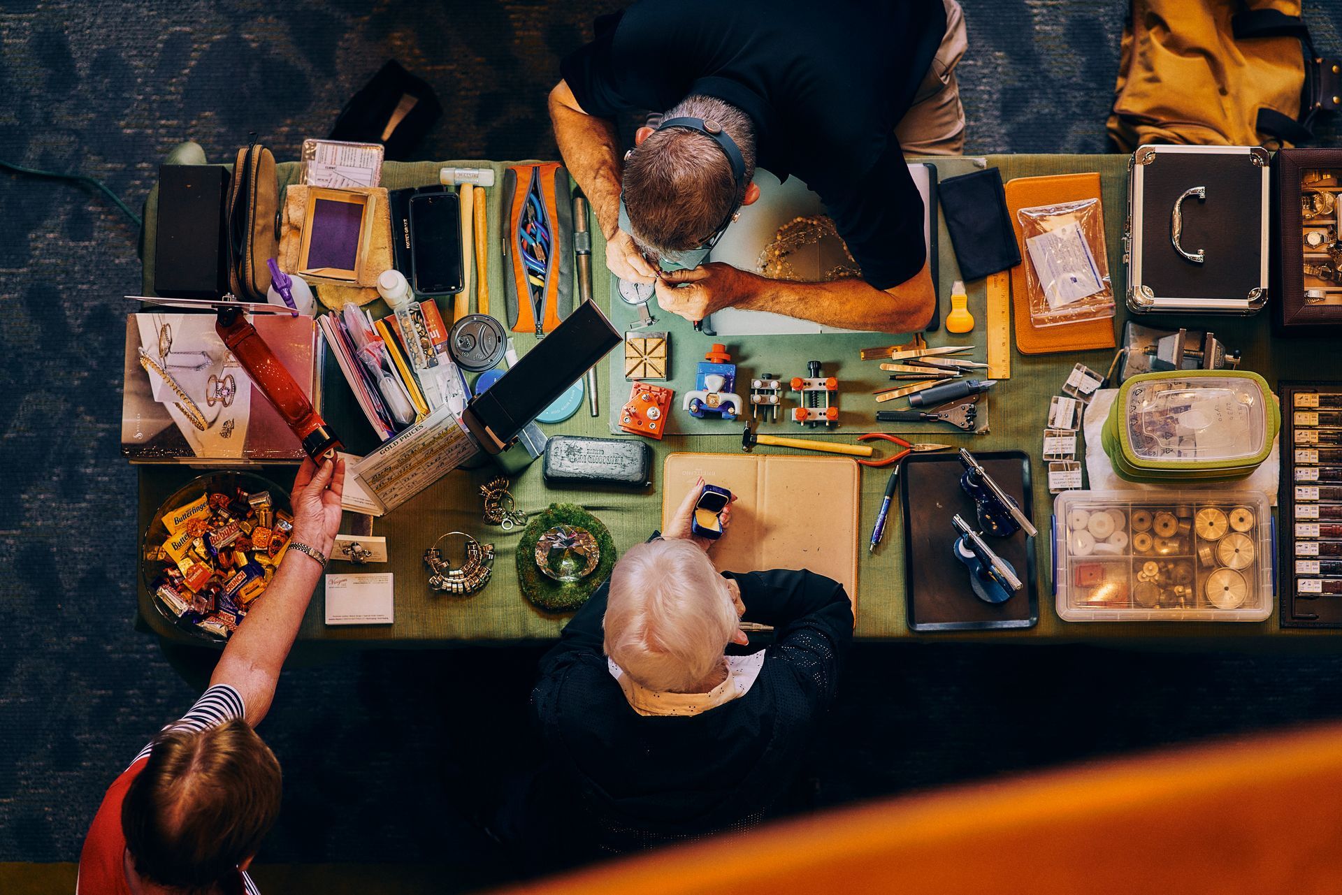 A man and a woman are sitting at a table making jewelry.