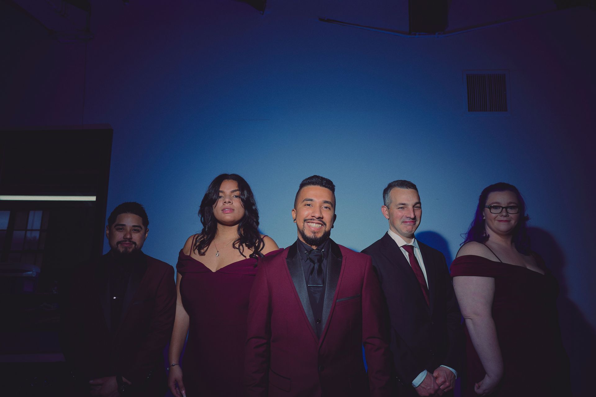 A group of people standing next to each other in front of a blue wall.