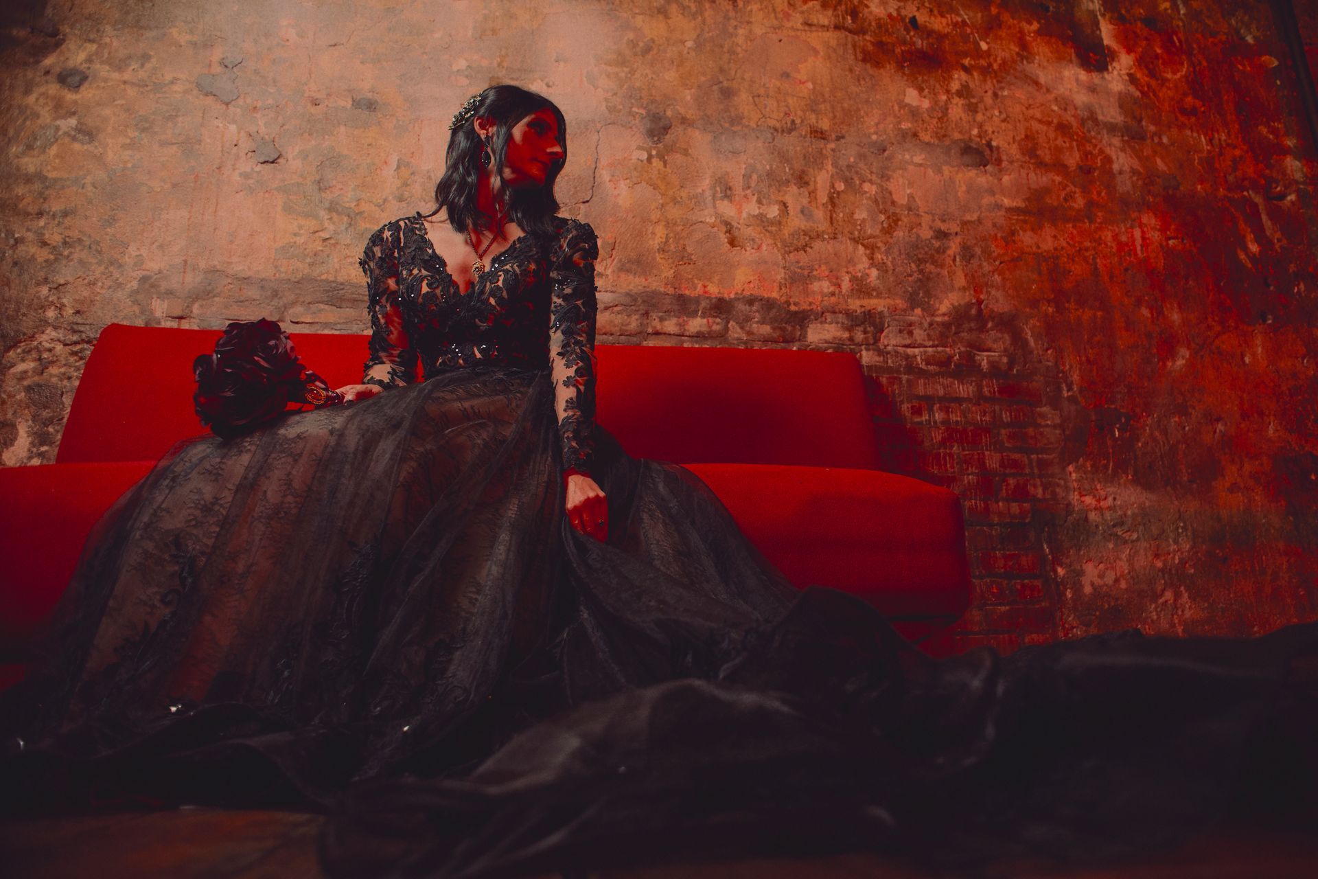 A woman in a black dress is sitting on a red couch.