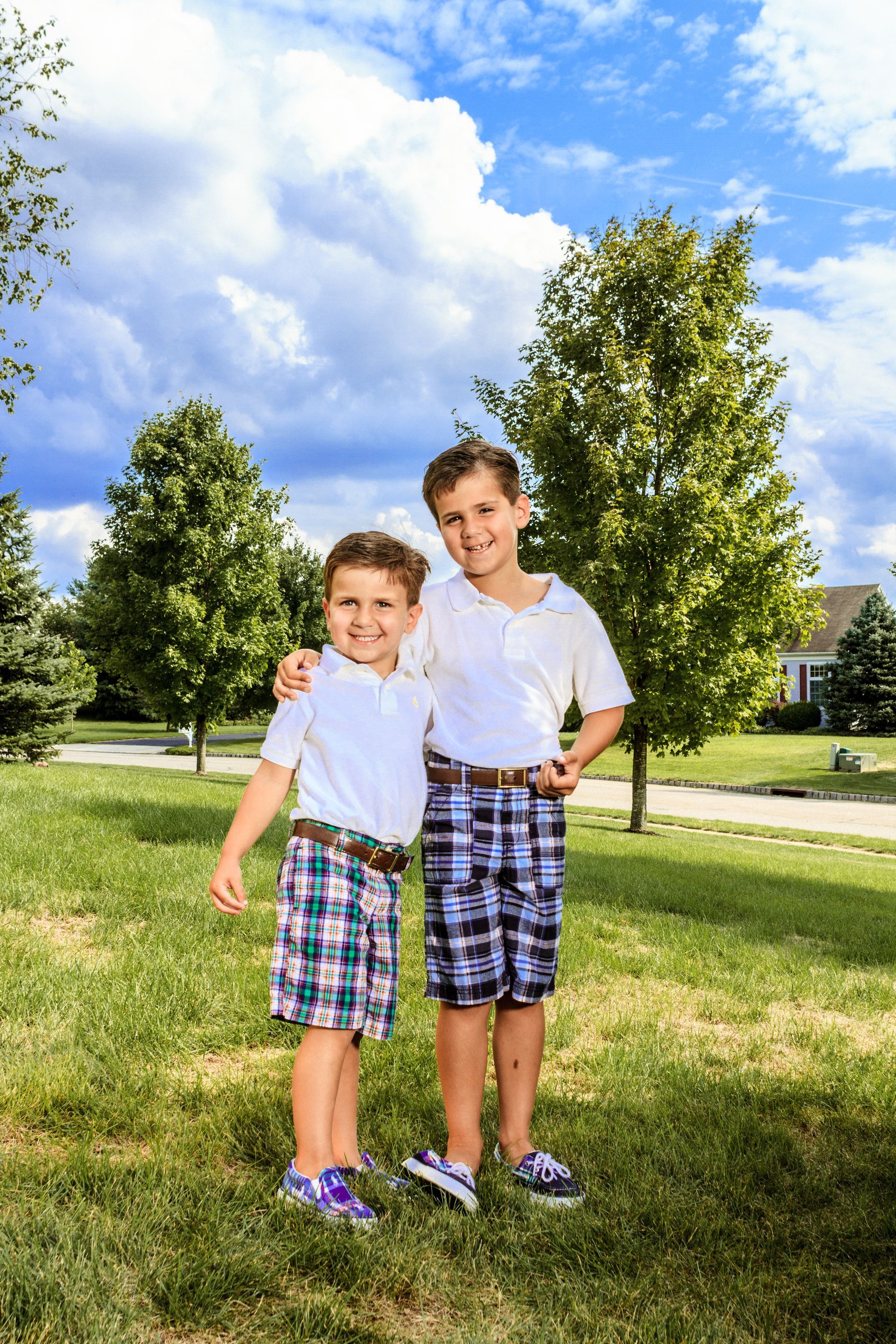 Two young boys are standing next to each other in a park.