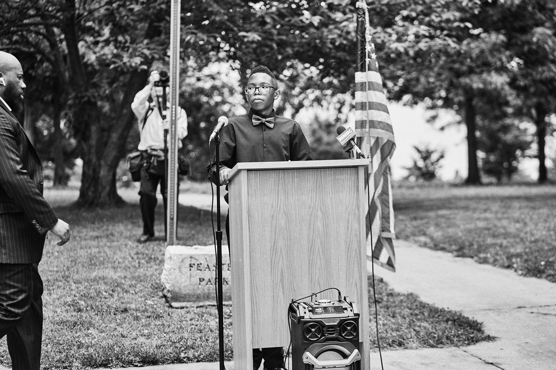 A man is standing at a podium speaking into a microphone.