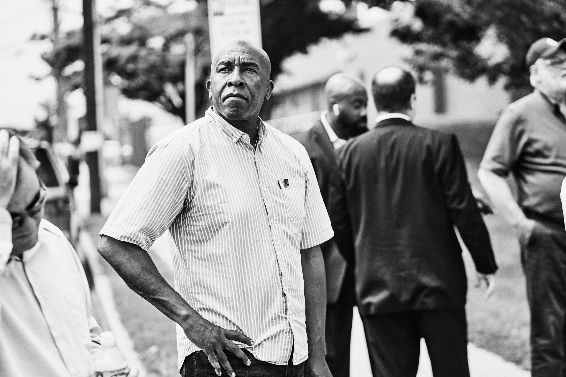 A man in a striped shirt is standing in a crowd of people.