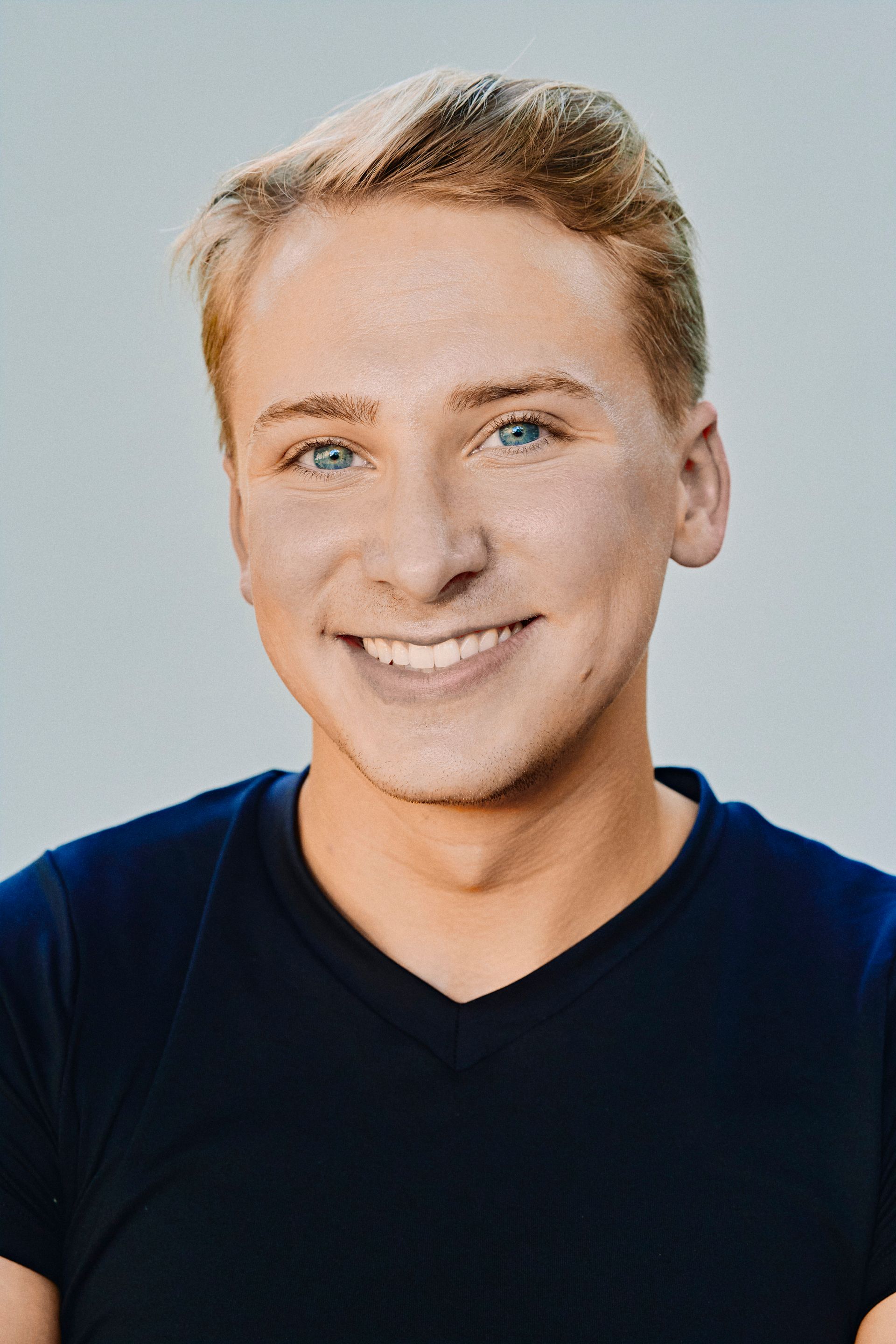 Smiling person with blonde hair wearing a blue shirt.