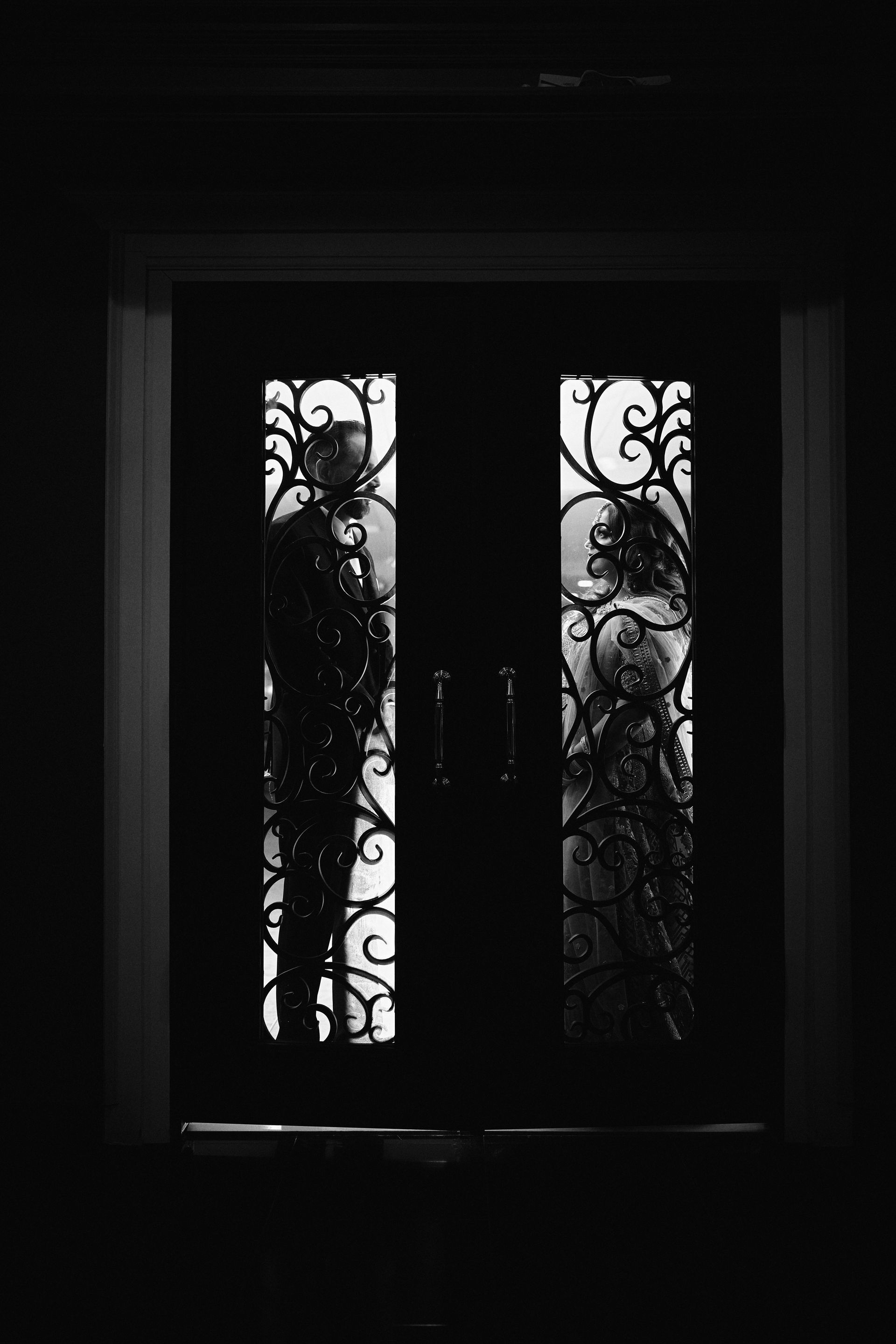 A black and white photo of a door with a wrought iron design.