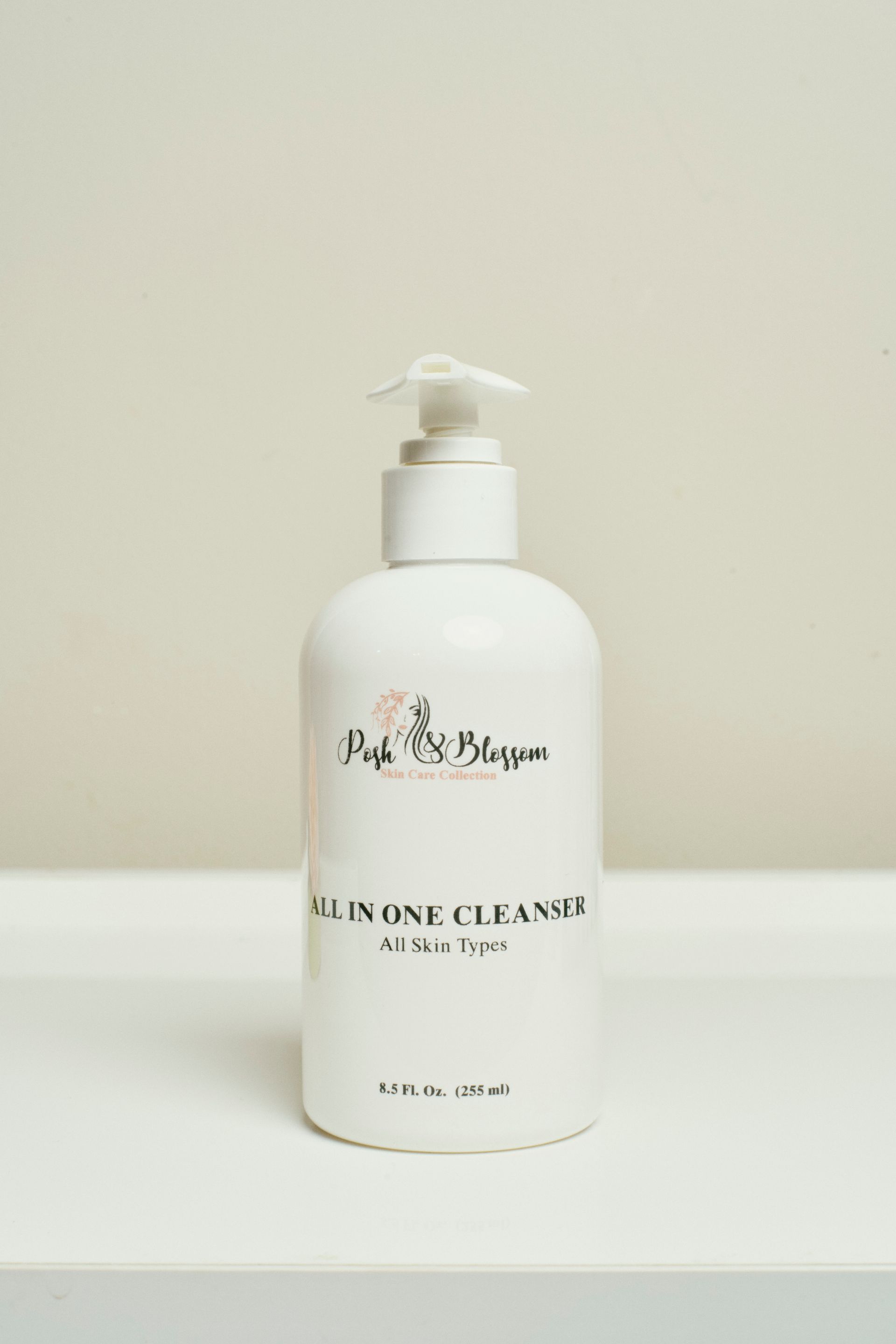 A white bottle of all in one cleanser is sitting on a white table.