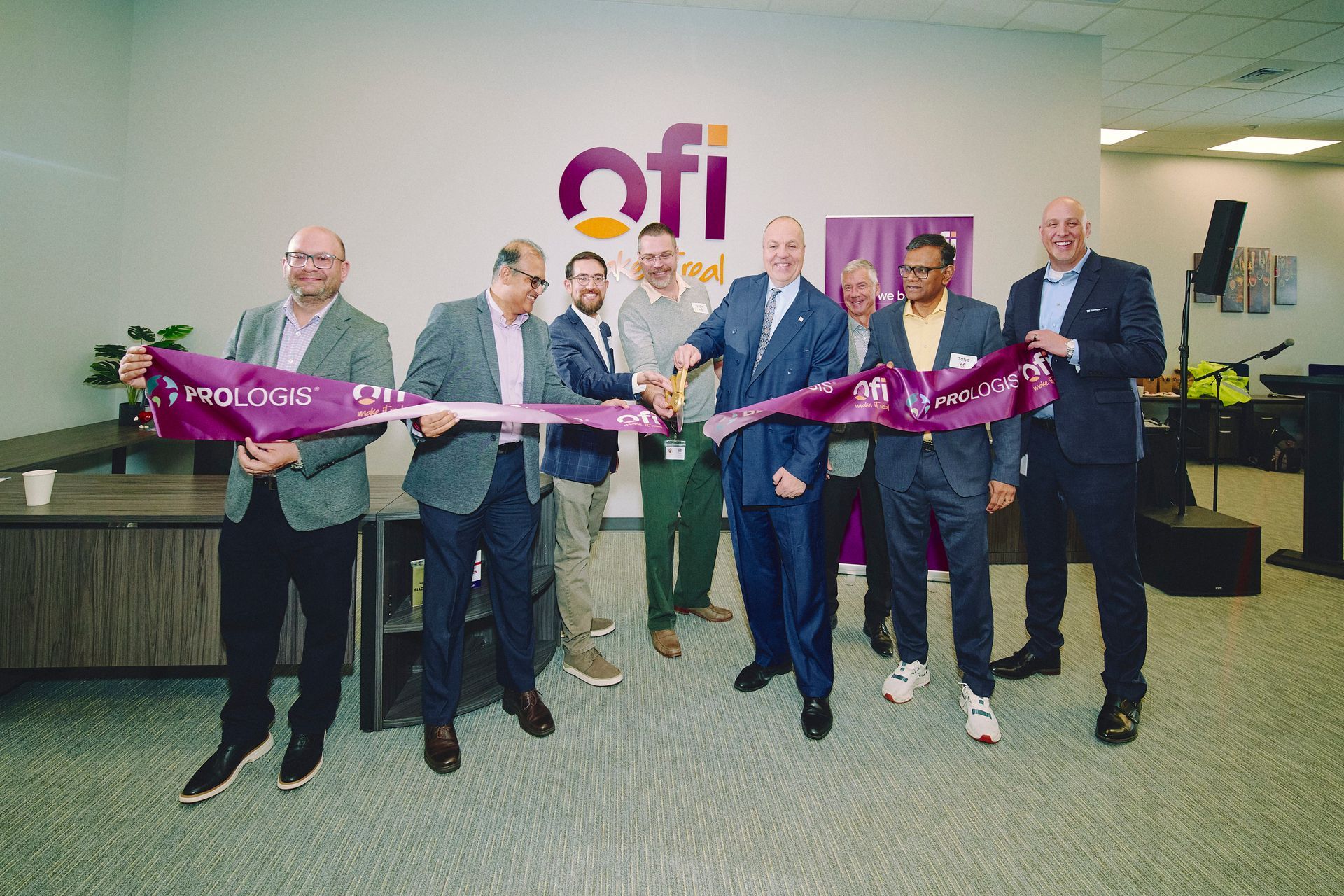 People cutting a ribbon at an office; 