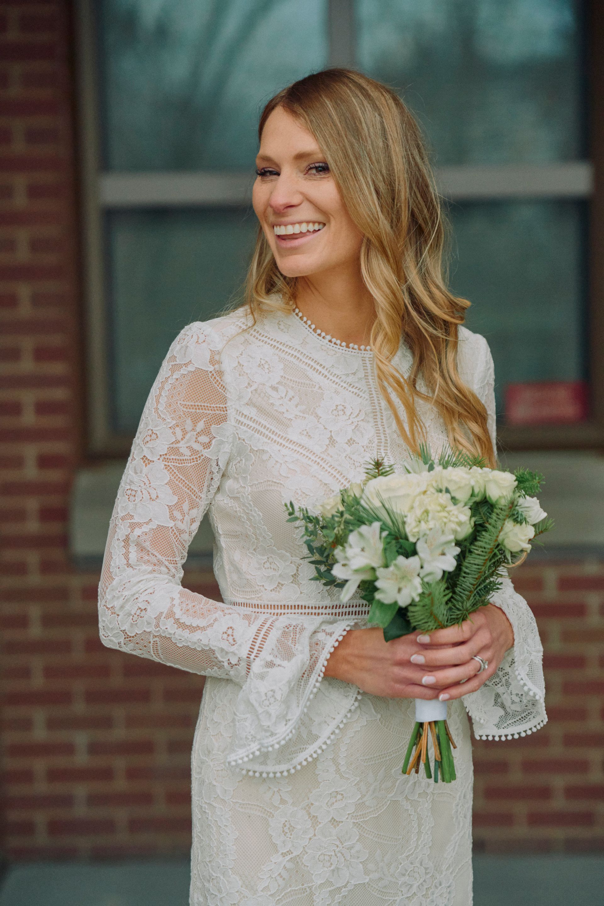 The bride is wearing a white lace dress and holding a bouquet of flowers.