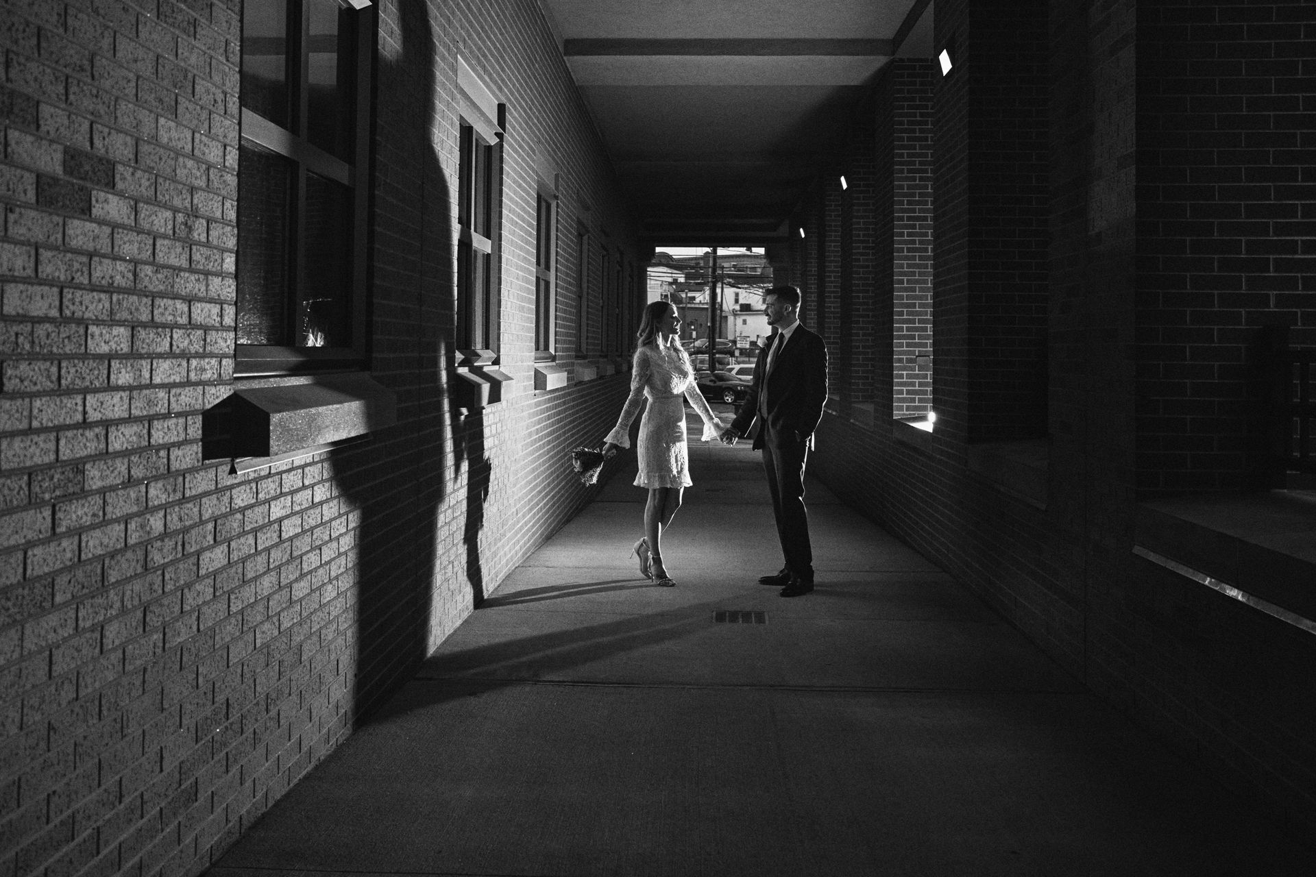 A black and white photo of a man and woman standing in a hallway.