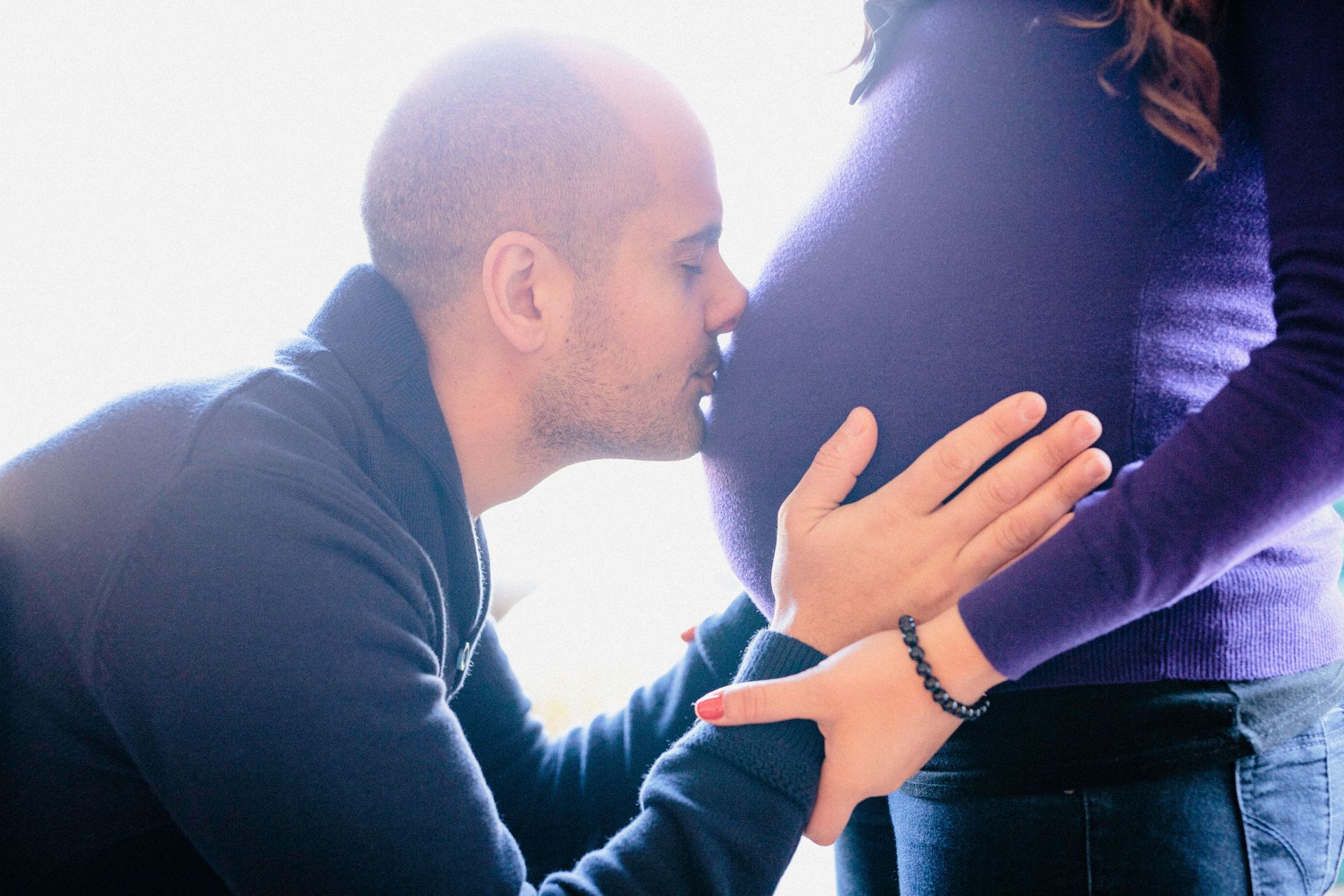 A man kissing the belly of a pregnant woman.