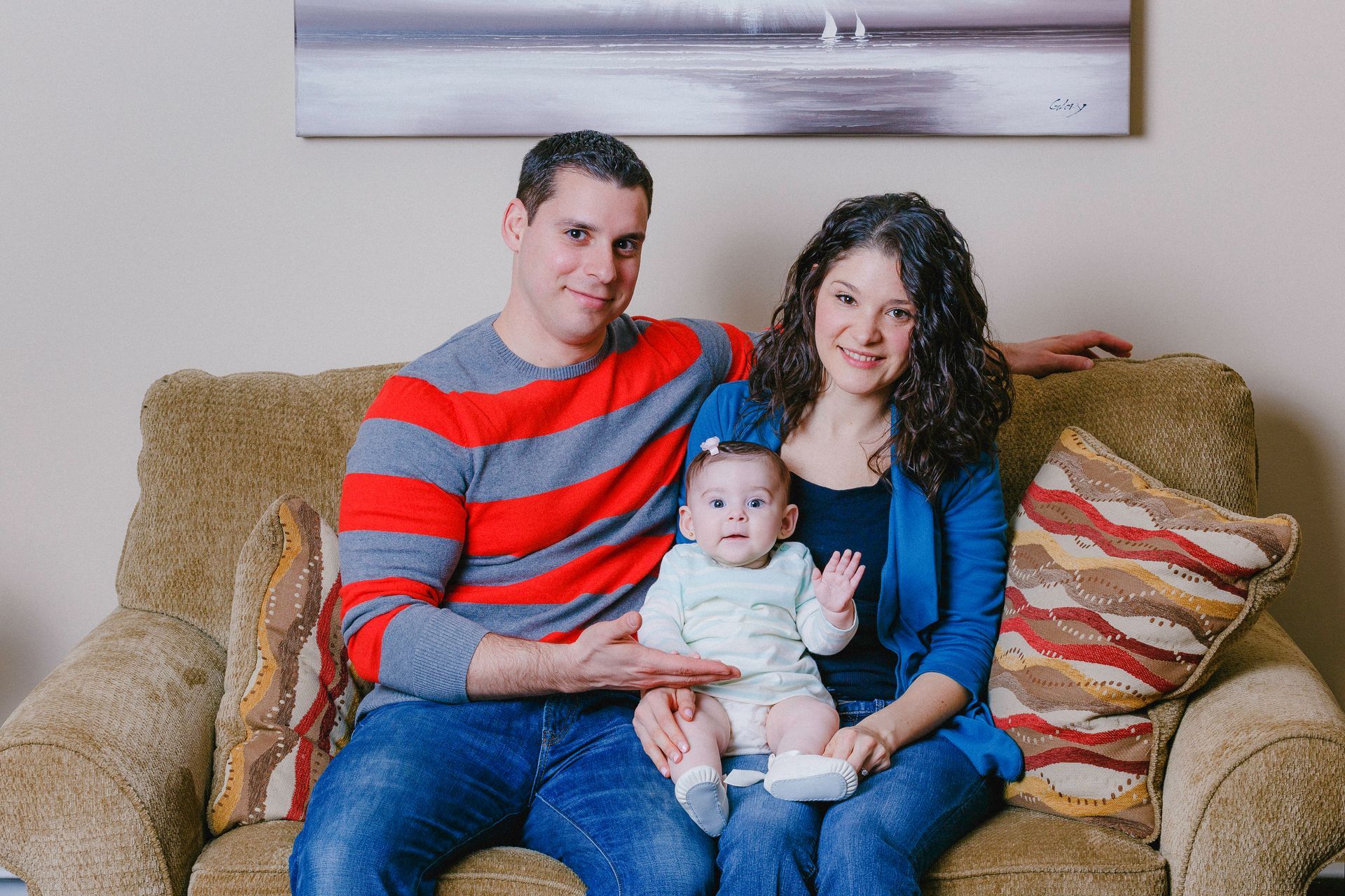 A man and woman are sitting on a couch with a baby.