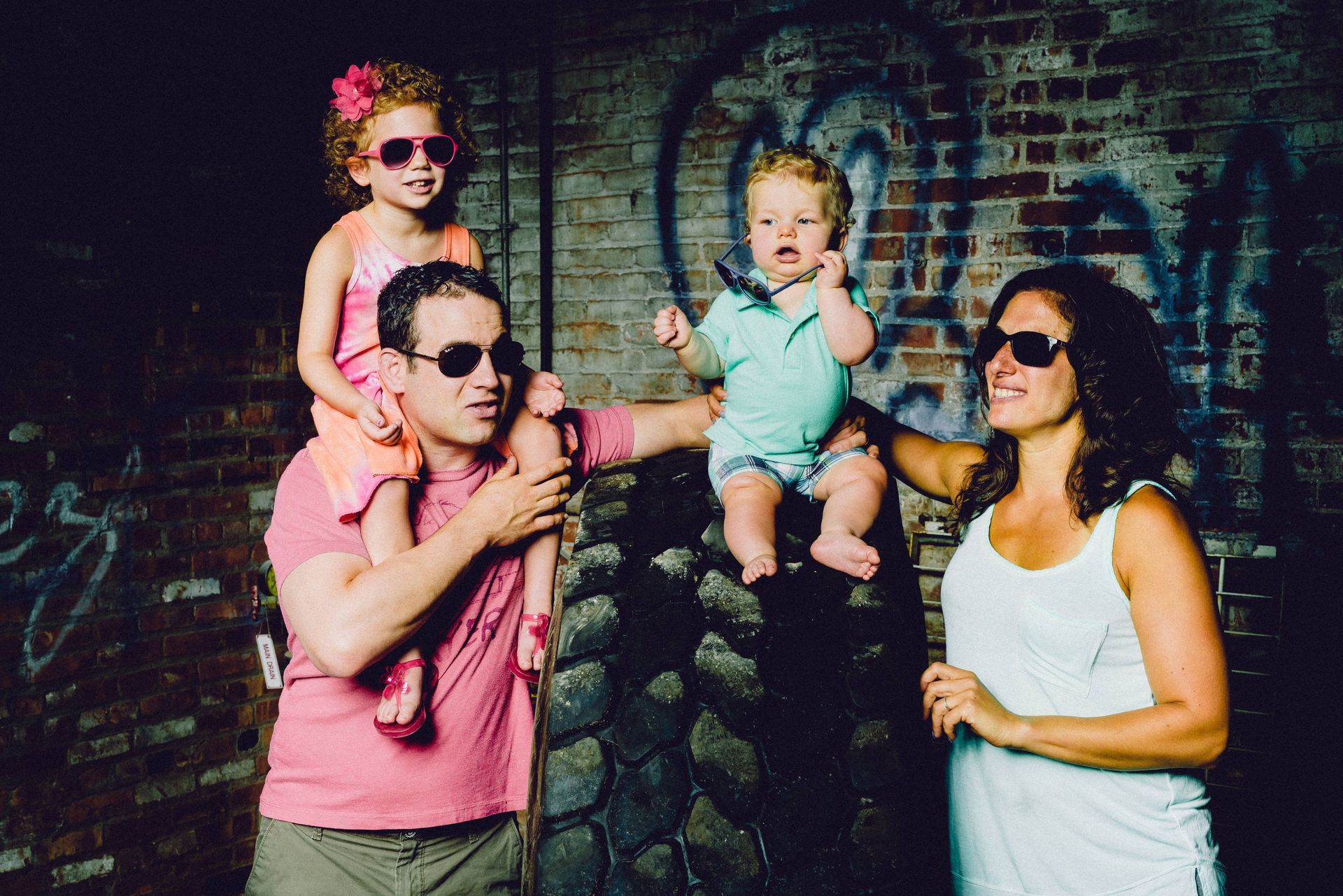 A family is posing for a picture in front of a brick wall.