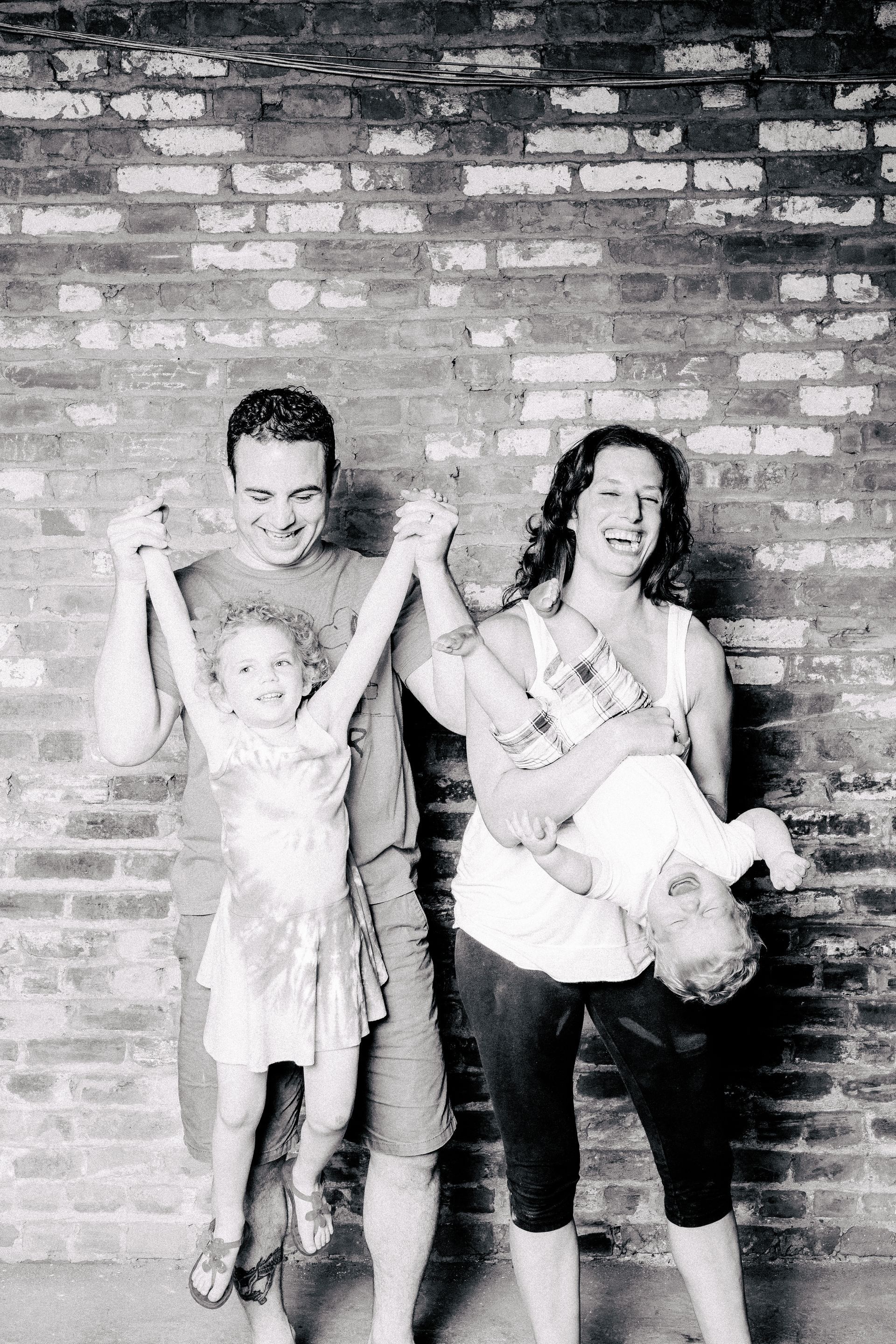 A black and white photo of a family standing in front of a brick wall.