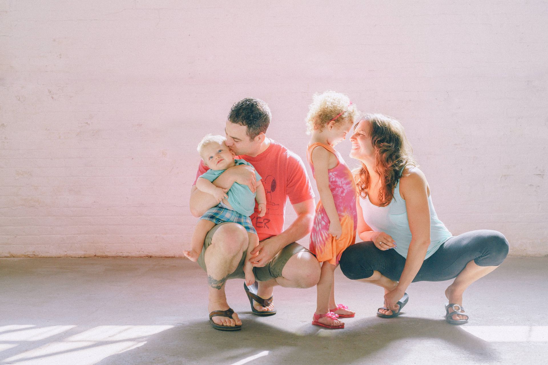 A family is posing for a picture together in front of a pink wall.